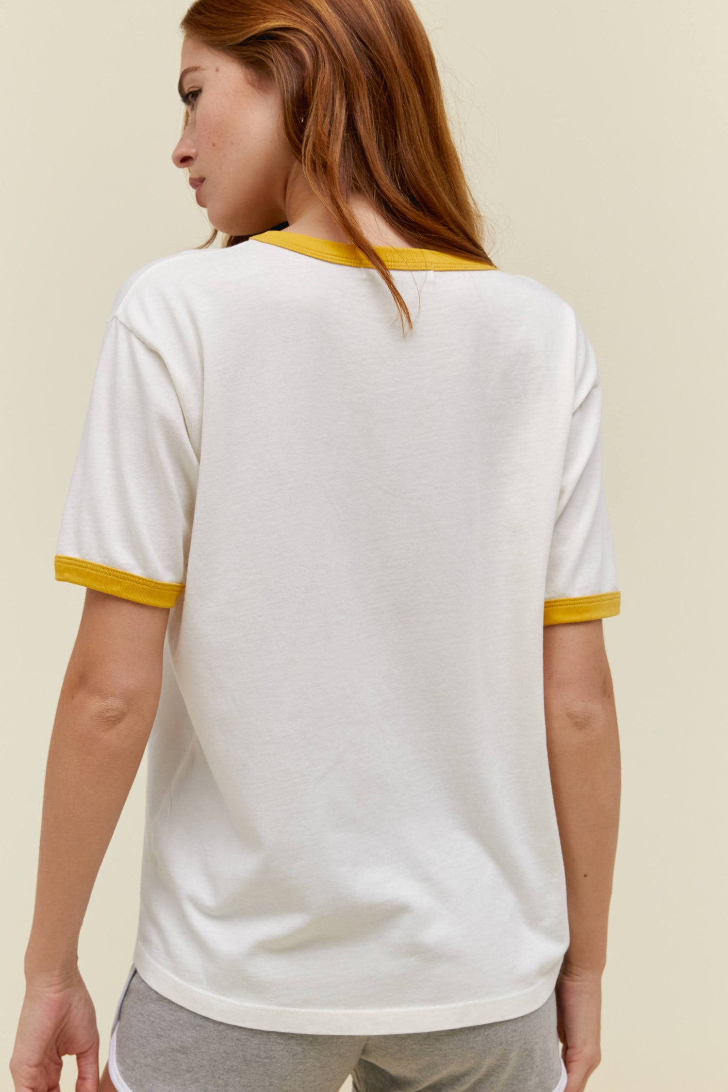 A model featuring a ringer tee with mustard-trimmed sleeves and neckline and adorned with "Beastie Boys" across the chest area