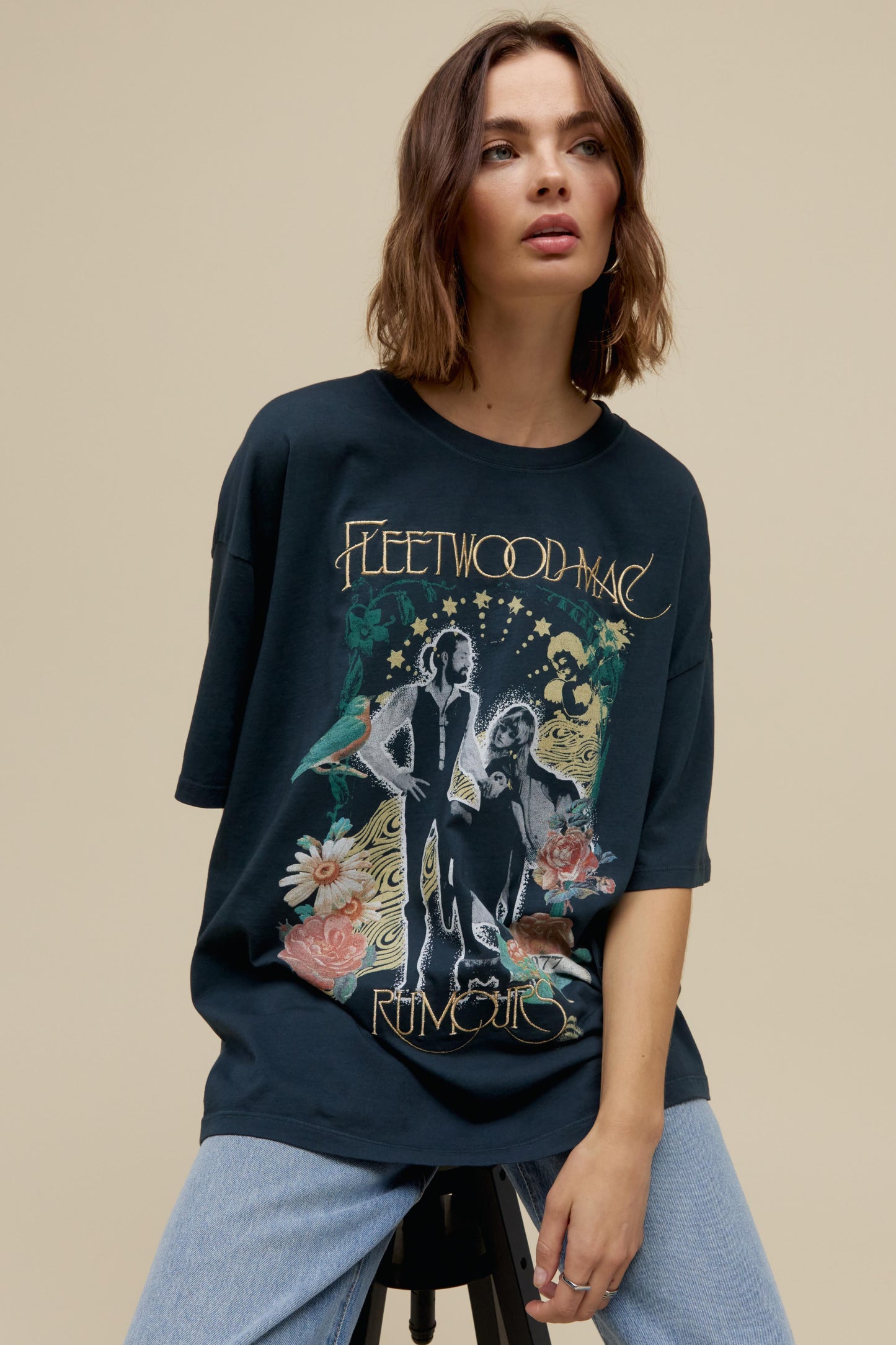 Short-haired model wearing an oversized Fleetwood Mac graphic tee with gold embroidery and floral artwork