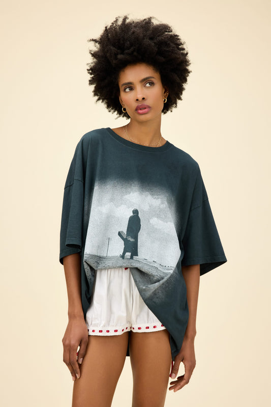 A model featuring a black os tee designed with a graphic of a man in the middle and stamped with Cash at the back.