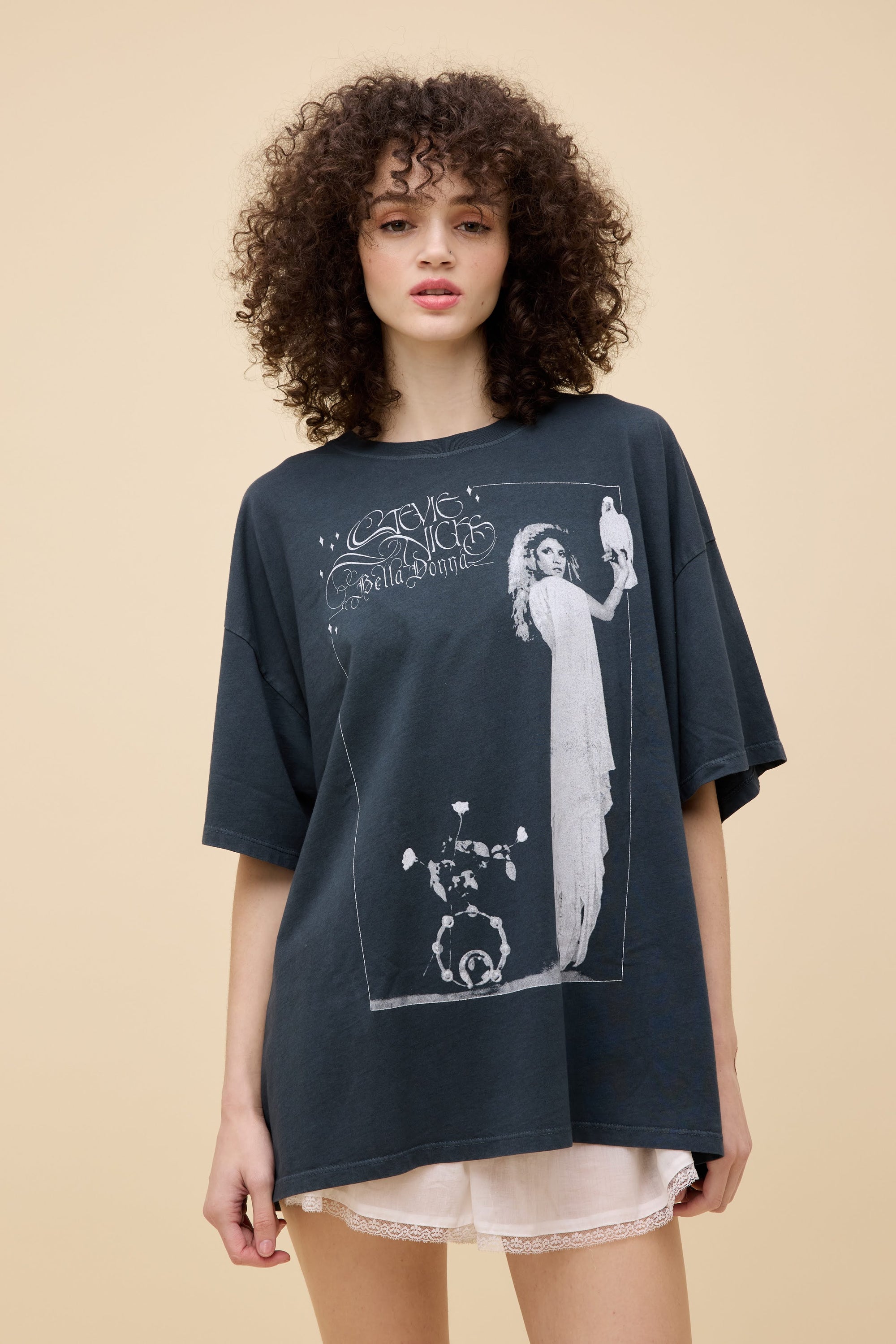 Model with curly hair in studio wearing a stevie nicks graphic tee.