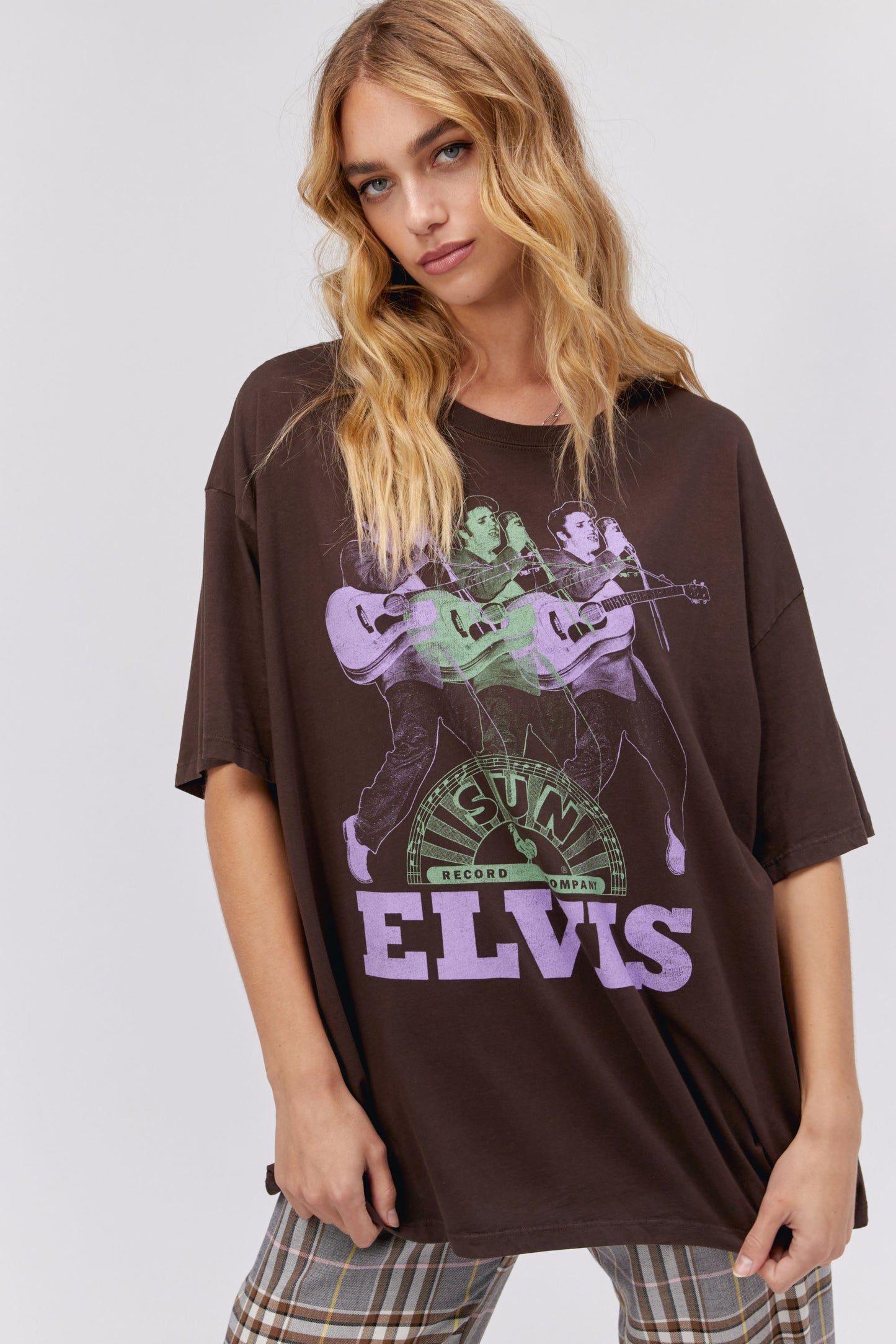 A blonde-haired model featuring a brown tee stamped with the legendary artist's name and his iconic portrait in green and purple inks.