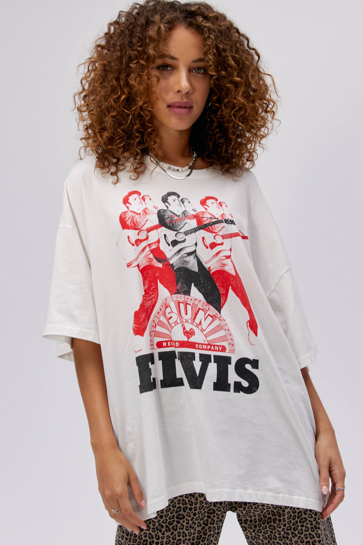 A curly-haired model featuring a white tee stamped with the legendary artist's name and his iconic portrait in red and black inks.