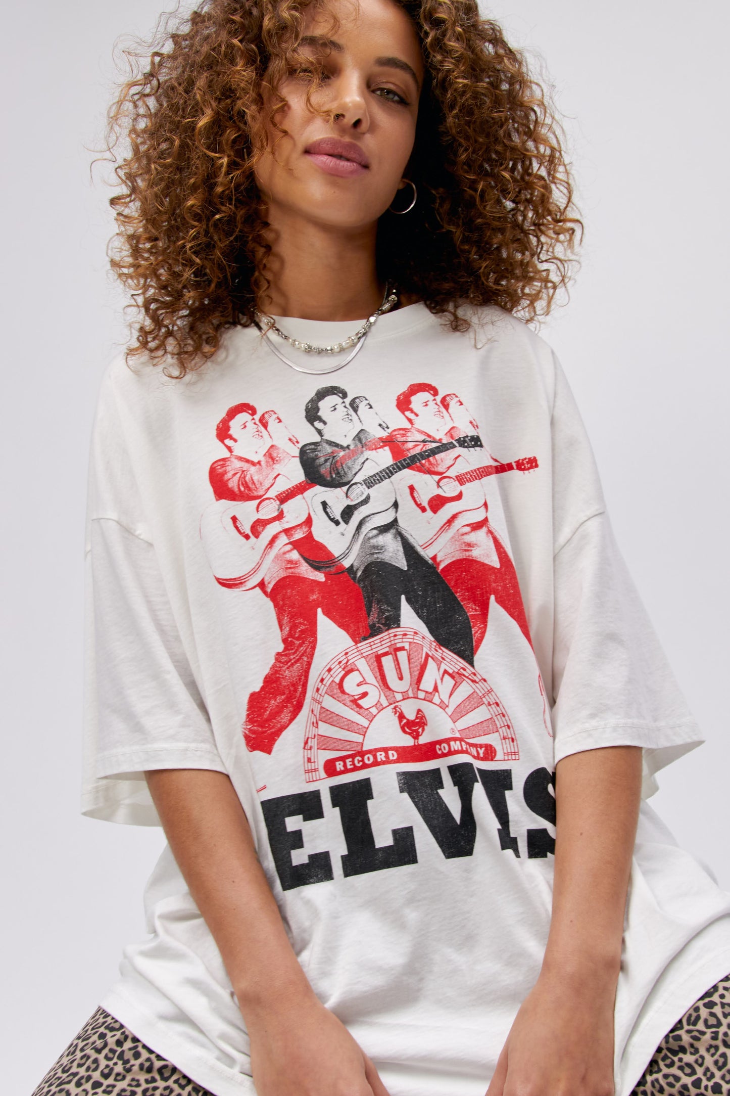 A curly-haired model featuring a white tee stamped with the legendary artist's name and his iconic portrait in red and black inks.