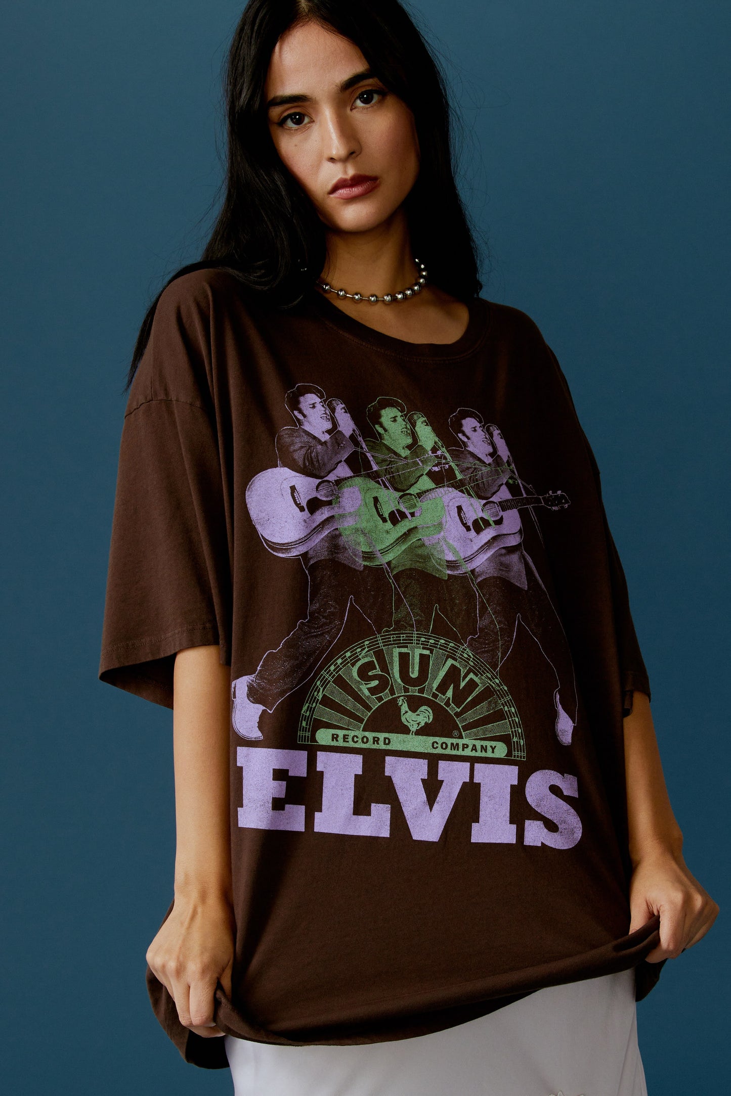 A dark-haired model featuring a brown tee stamped with the legendary artist's name and his iconic portrait in green and purple inks.