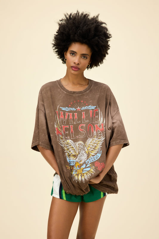 A model featuring a brown os tee stamped with Willie Nelson and a graphic of an eagle at the middle.