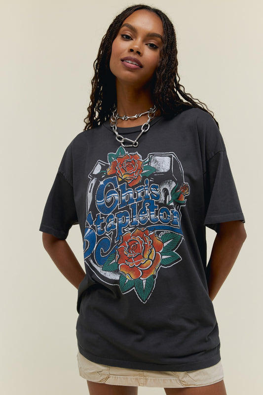 A model featuring a black merch tee stamped with 'Chris Stapleton' in the middle with flowers around.