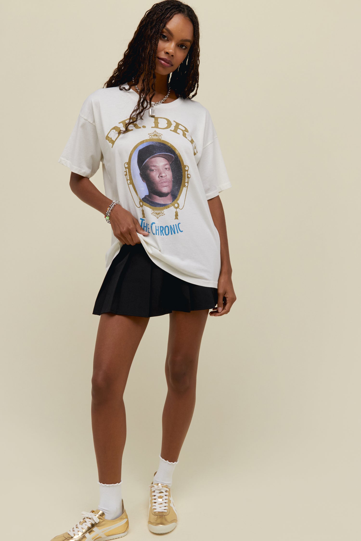 A dark-haired model featuring a white tee designed with the album's cover artwork accented in gold ink and featuring a portrait of the legend.