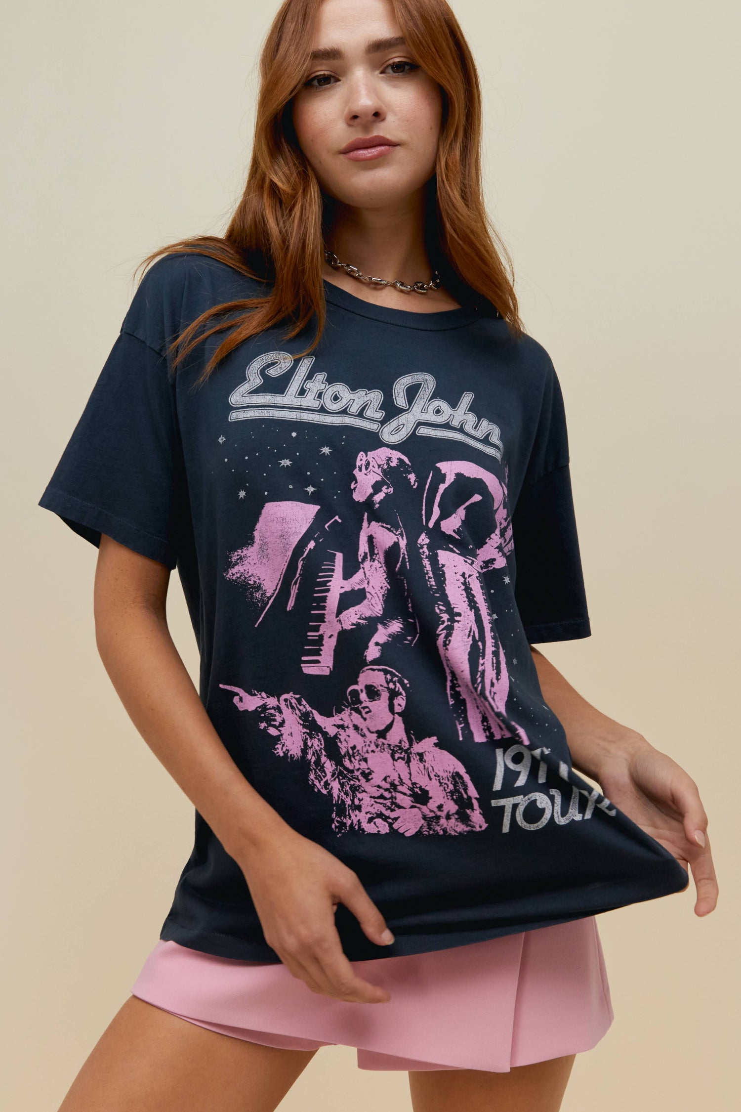 Model wearing a vintage black Elton John 1997 Tour graphic tee with contrast pink artwork.