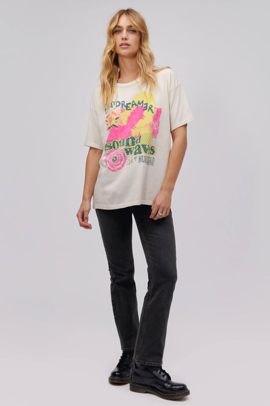 A blonde-haired model featuring a white tee stamped with 'daydreamer' and 'sound waves' at the back. It is also designed with pink and yellow graphics.