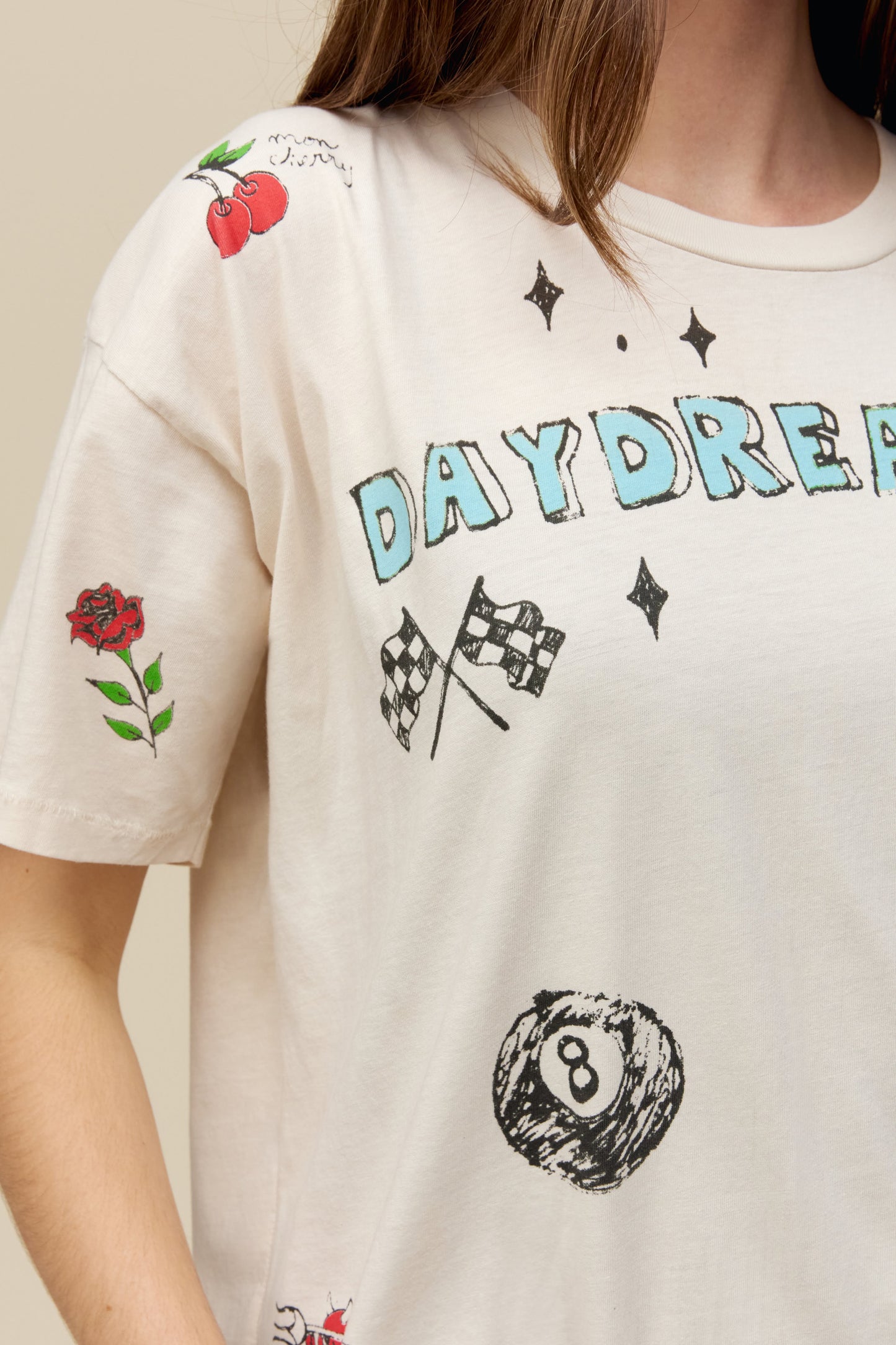 A model featuring a white tee stamped with daydreamer and designed with hand-drawn symbols.