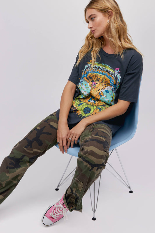 A blonde-haired model featuring a black tee designed with trees, flowers, and bear artwork and stamped with 'Grateful Dead' on top.