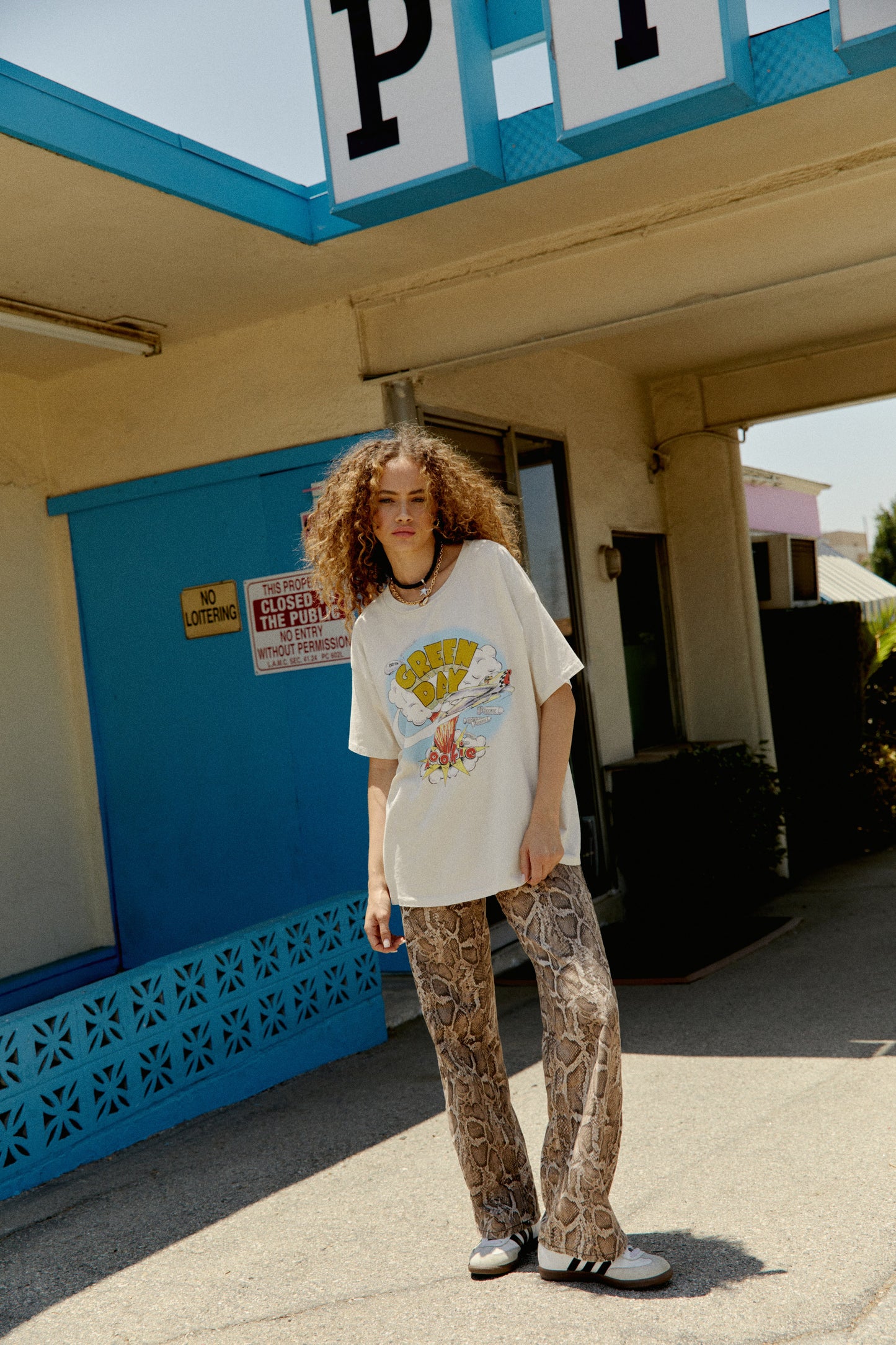 A curly-haired model featuring a white tee designed with the Green Day's album Dookie cover.