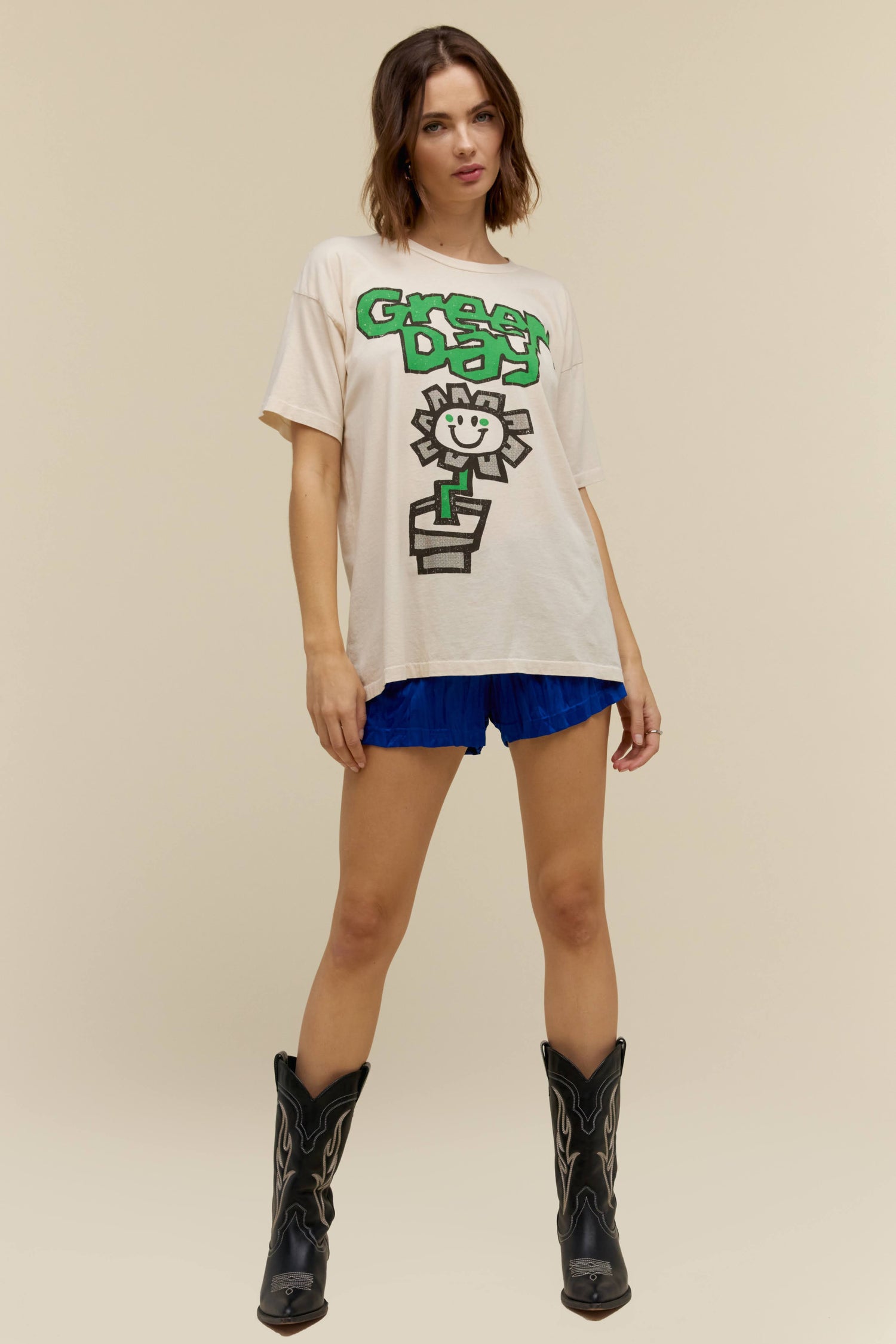 A model featuring a white tee stamped with 'Green Day' and a graphic flower pot in the middle.