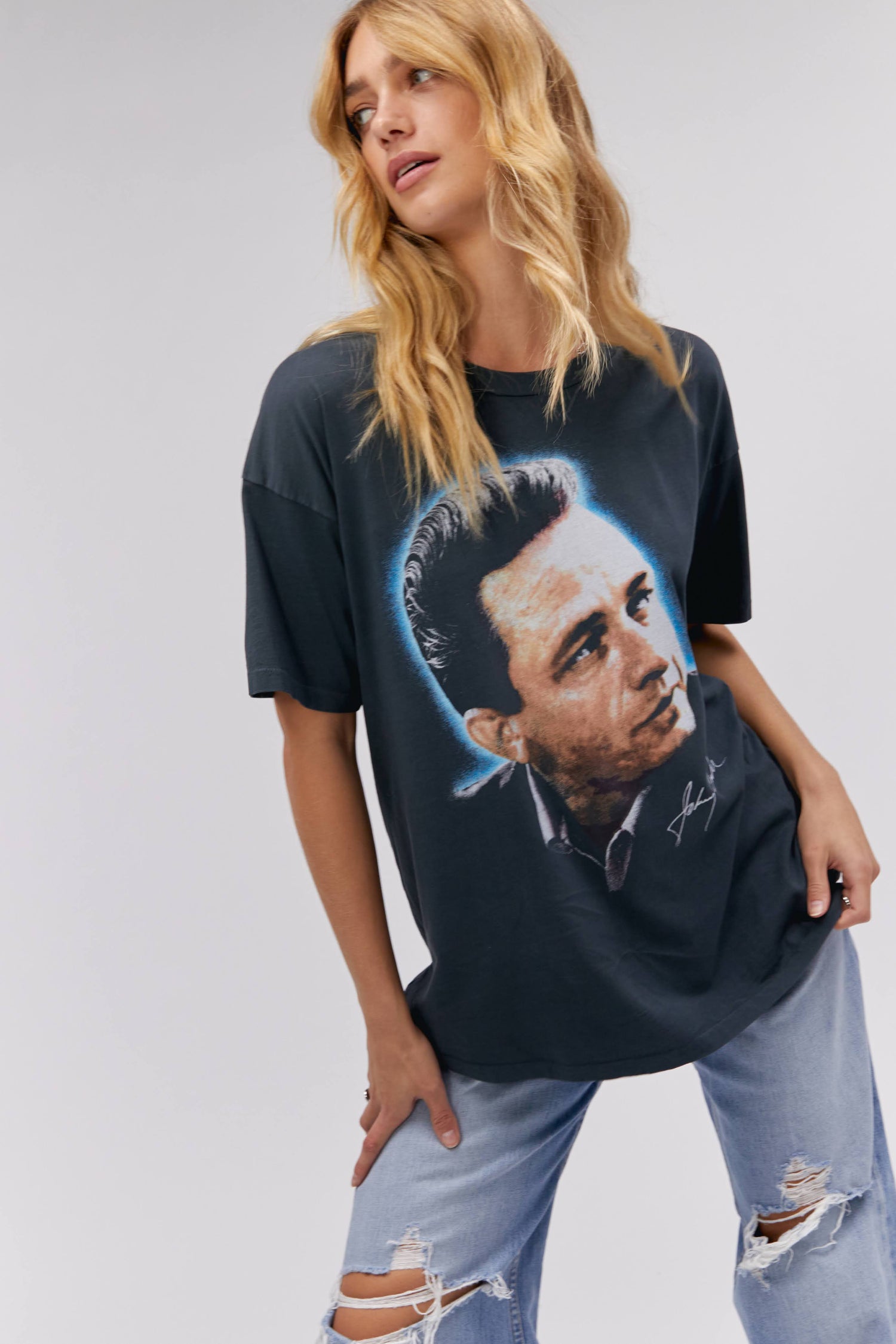 A blonde-haired model featuring a black tee designed with a portrait of Johnny Cash and stamped with 'Cash' at the back.
