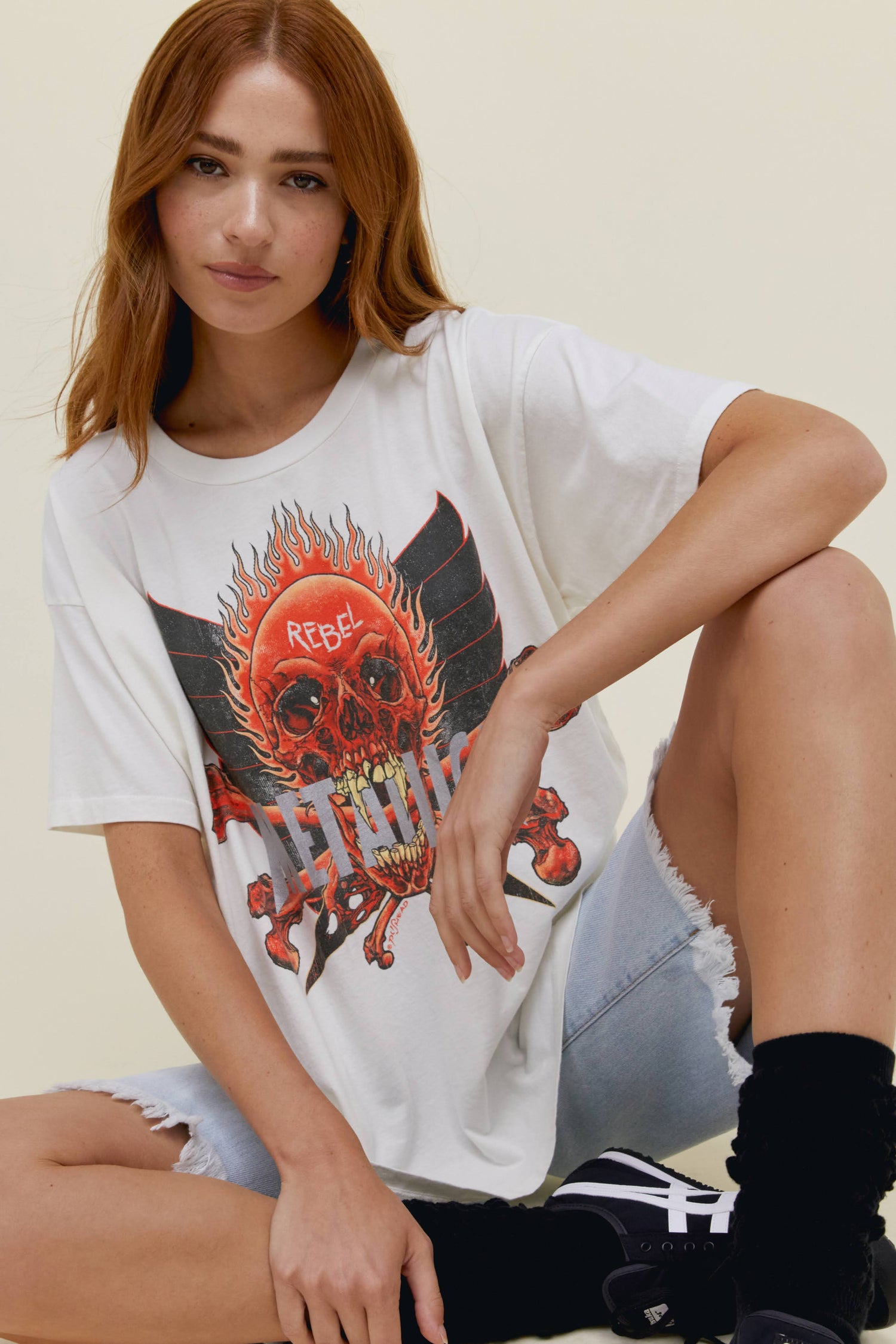A model featuring a white merch tee designedd with a graphic of a skull in the middle