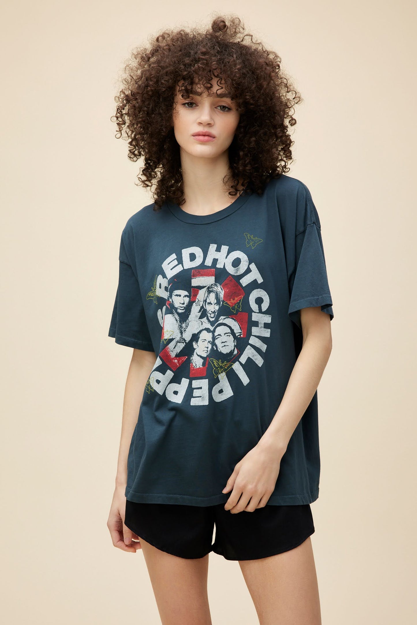 Curly-haired model wearing an oversized Red Hot Chili Peppers graphic tee.
