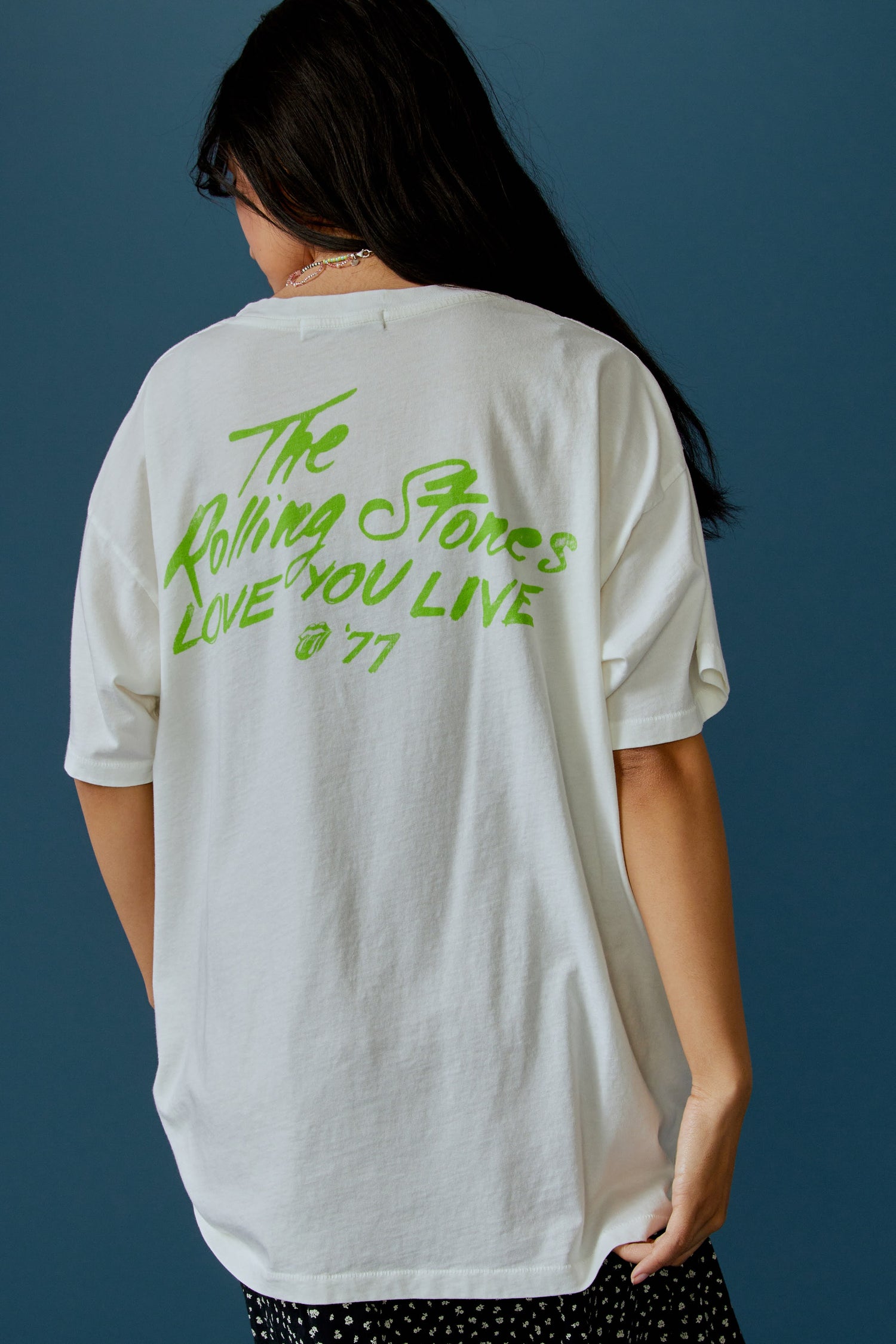A dark-haired model featuring a white tee designed with the Rolling Stones album cover, Love You Live.