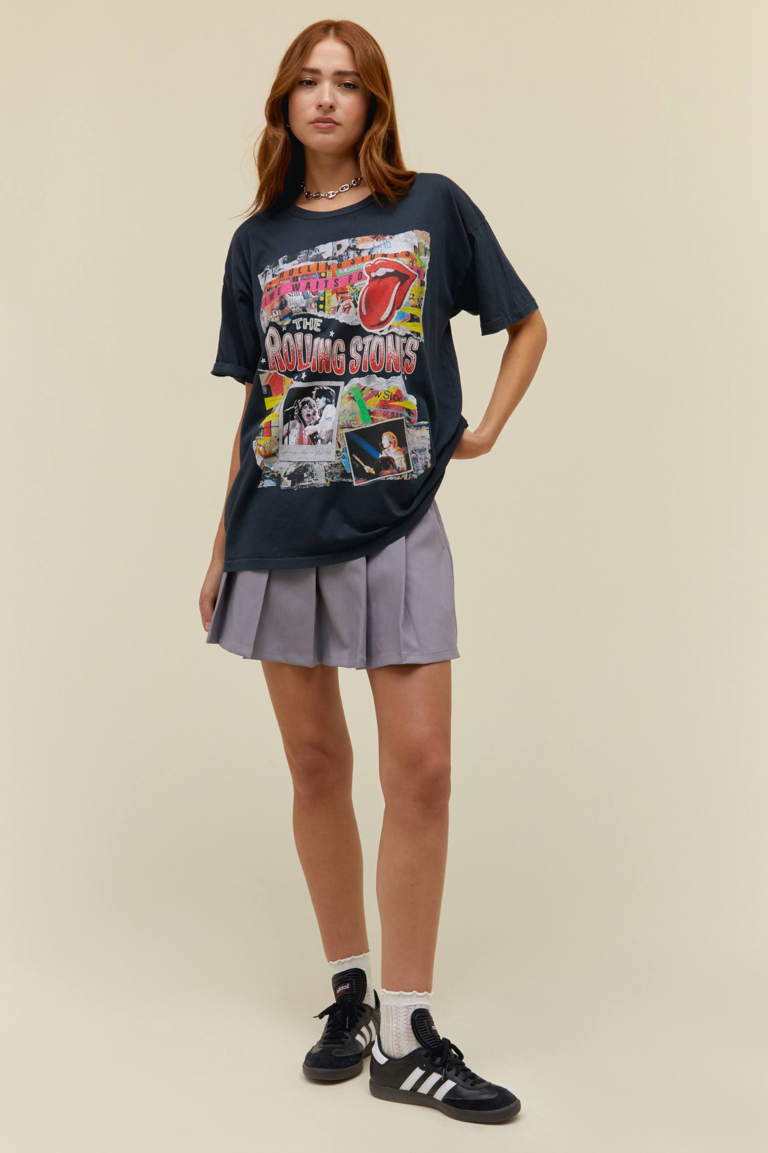A model featuring a black tee stamped with 'The Rolling Stones' wiith collage pictures of the band performing at concerts.