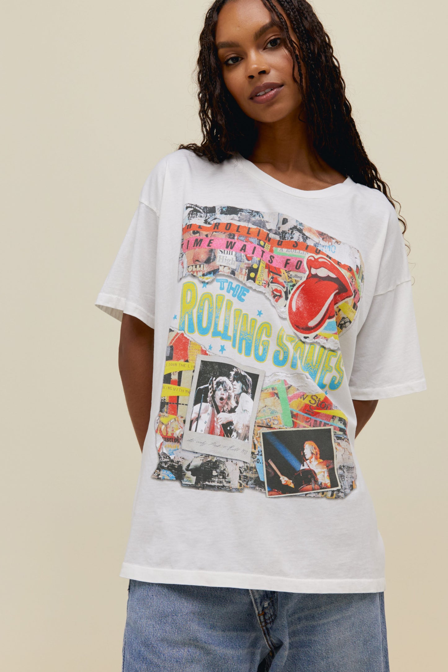 A model featuring a white tee stamped with 'The Rolling Stones' wiith collage pictures of the band performing at concerts.