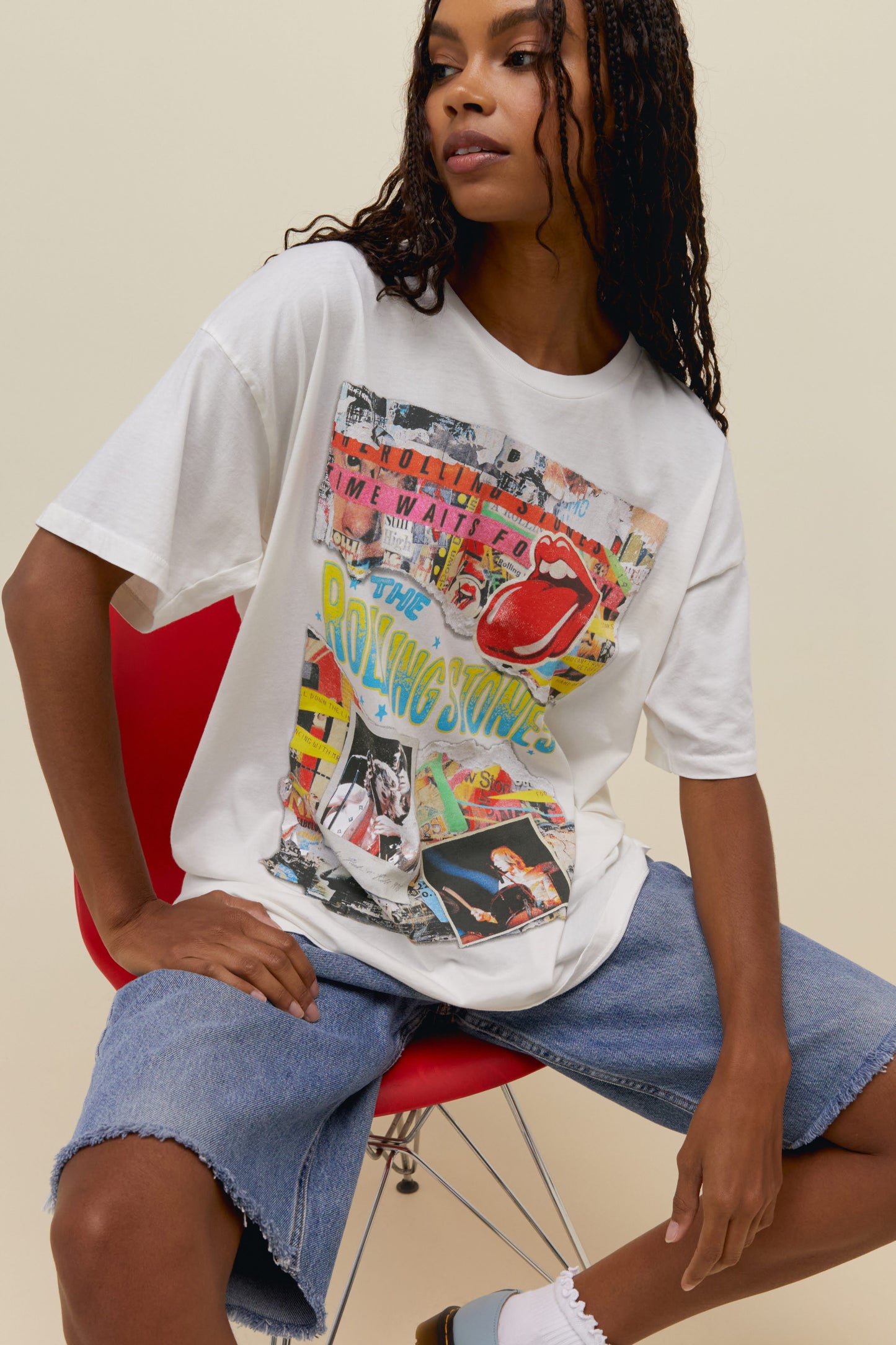 A model featuring a white tee stamped with 'The Rolling Stones' wiith collage pictures of the band performing at concerts.
