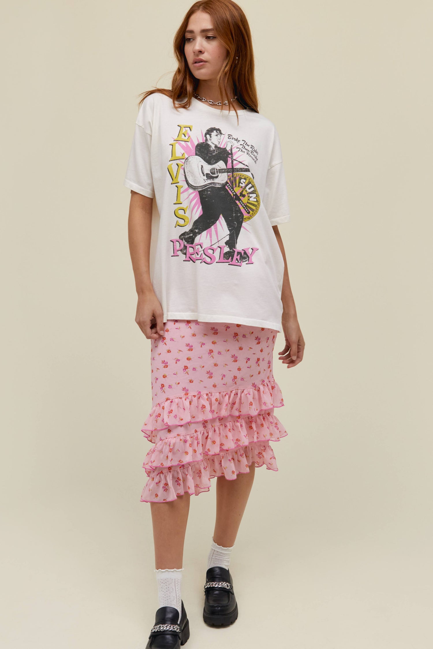 A straight-haired model featuring a white tee stamped with 'Elvis Presley' and an Iconic portrait of the asking.