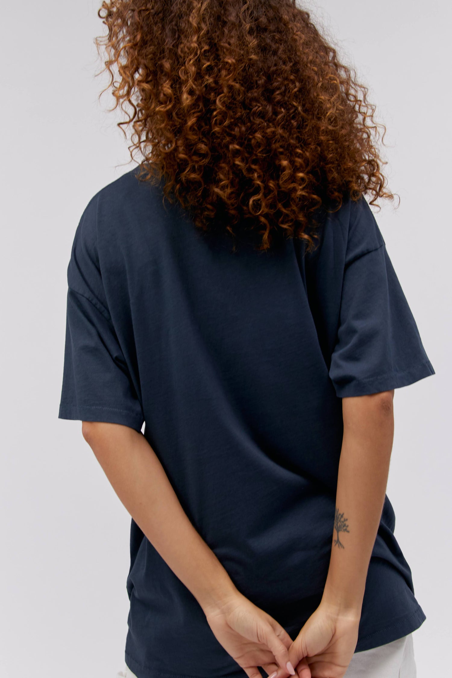 A curly-haired model featuring a black tee stamped with 'Wu-tang 36 Chambers' in red font and designed with the group's iconic 'W' logo  surrounded with a read dragon.