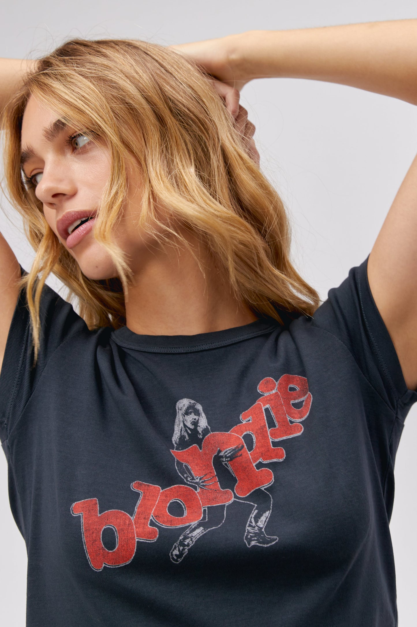 A blonde-haired model featuring a black tee stamped with 'blondie' in red, scattered letters.