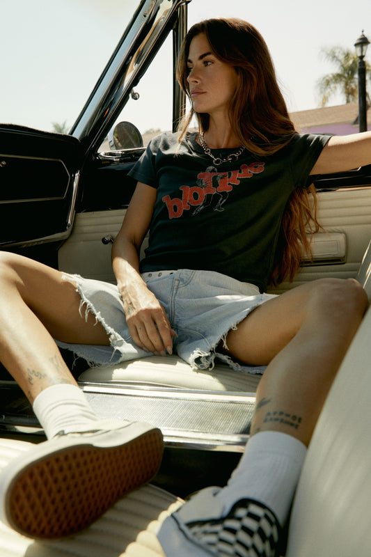 A dark-haired model featuring a black tee stamped with 'blondie' in red, scattered letters.
