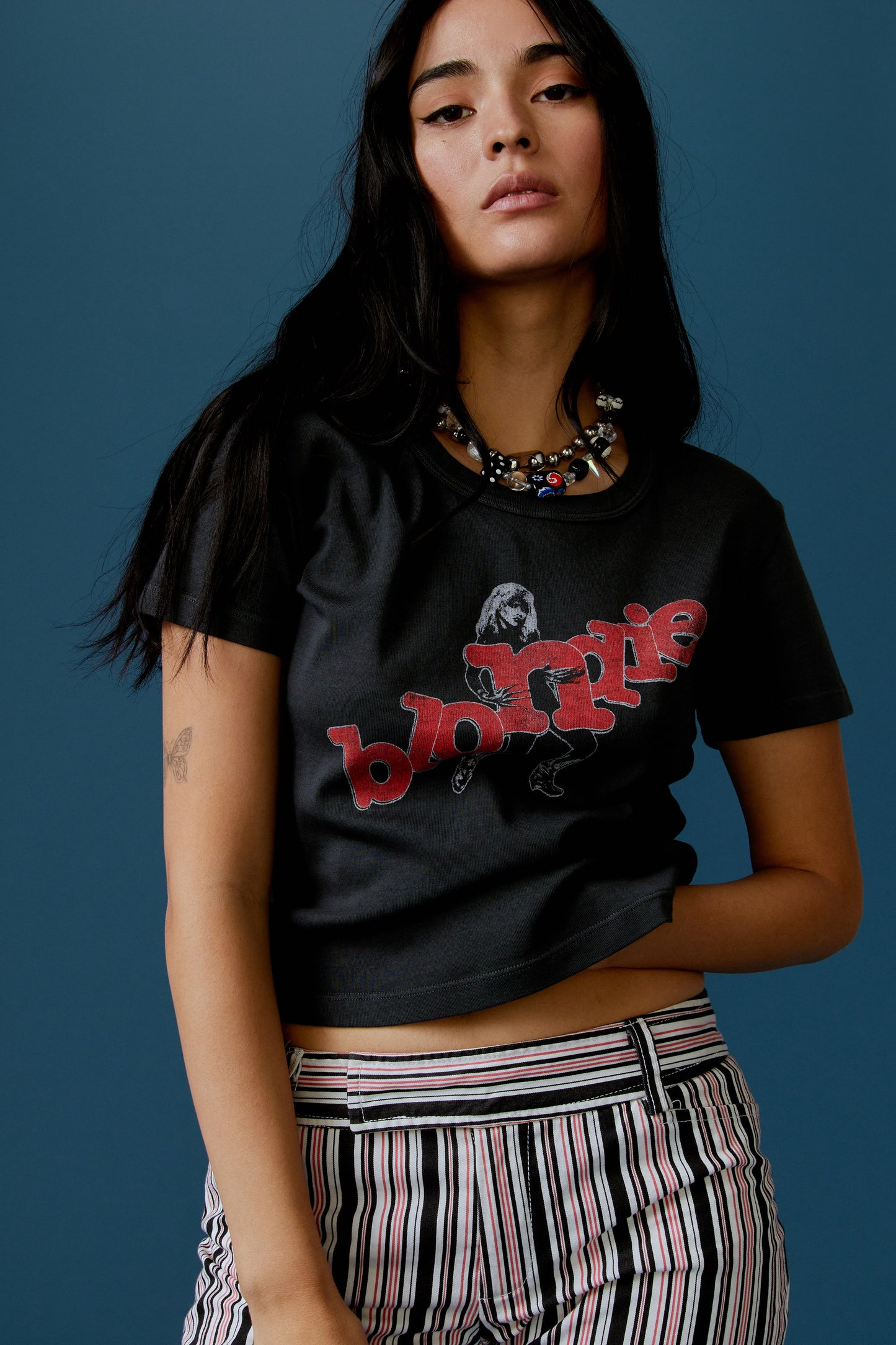 A dark-haired model featuring a black tee stamped with 'blondie' in red, scattered letters.