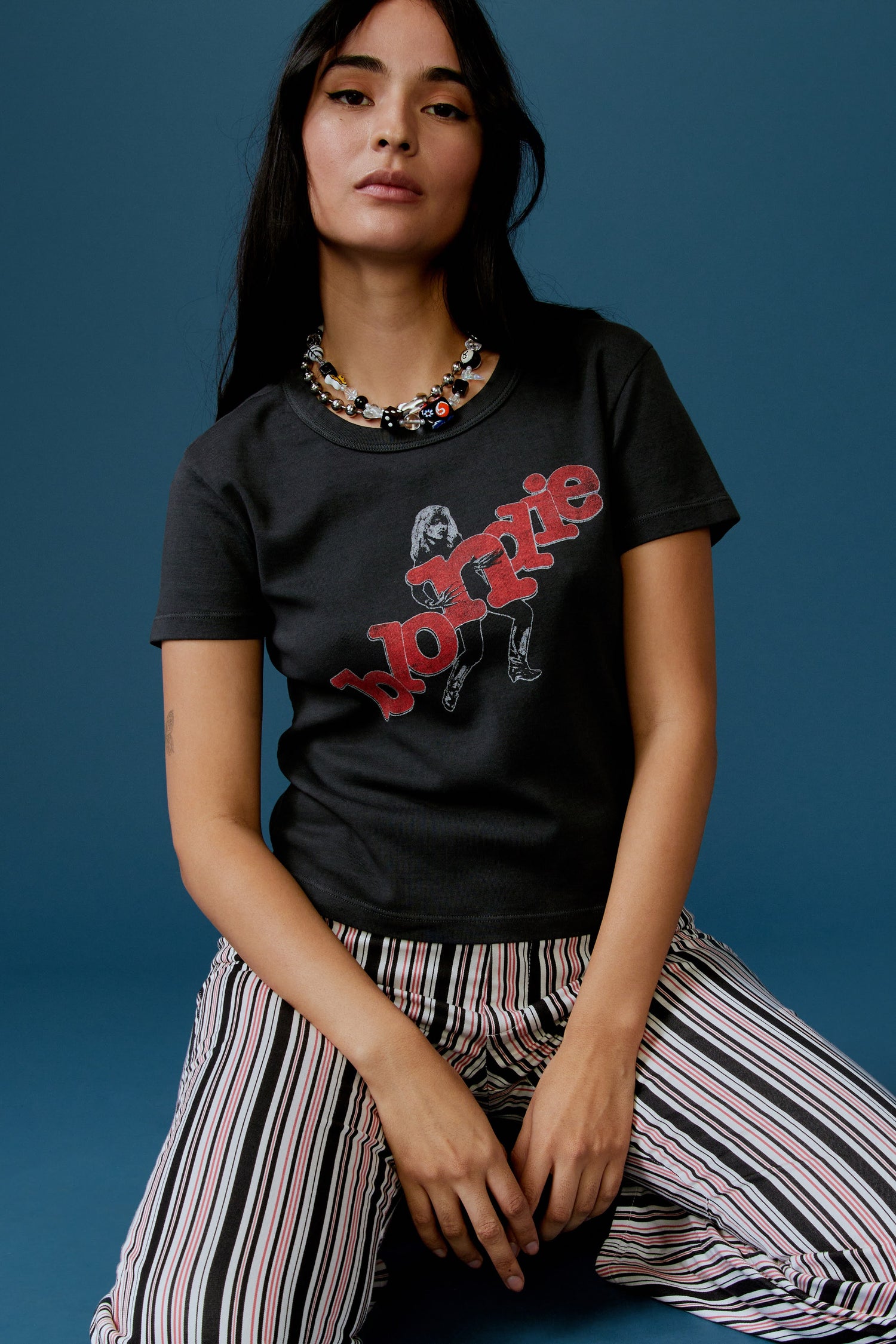 A dark-haired model featuring a black tee stamped with 'blondie' in red, scattered letters.