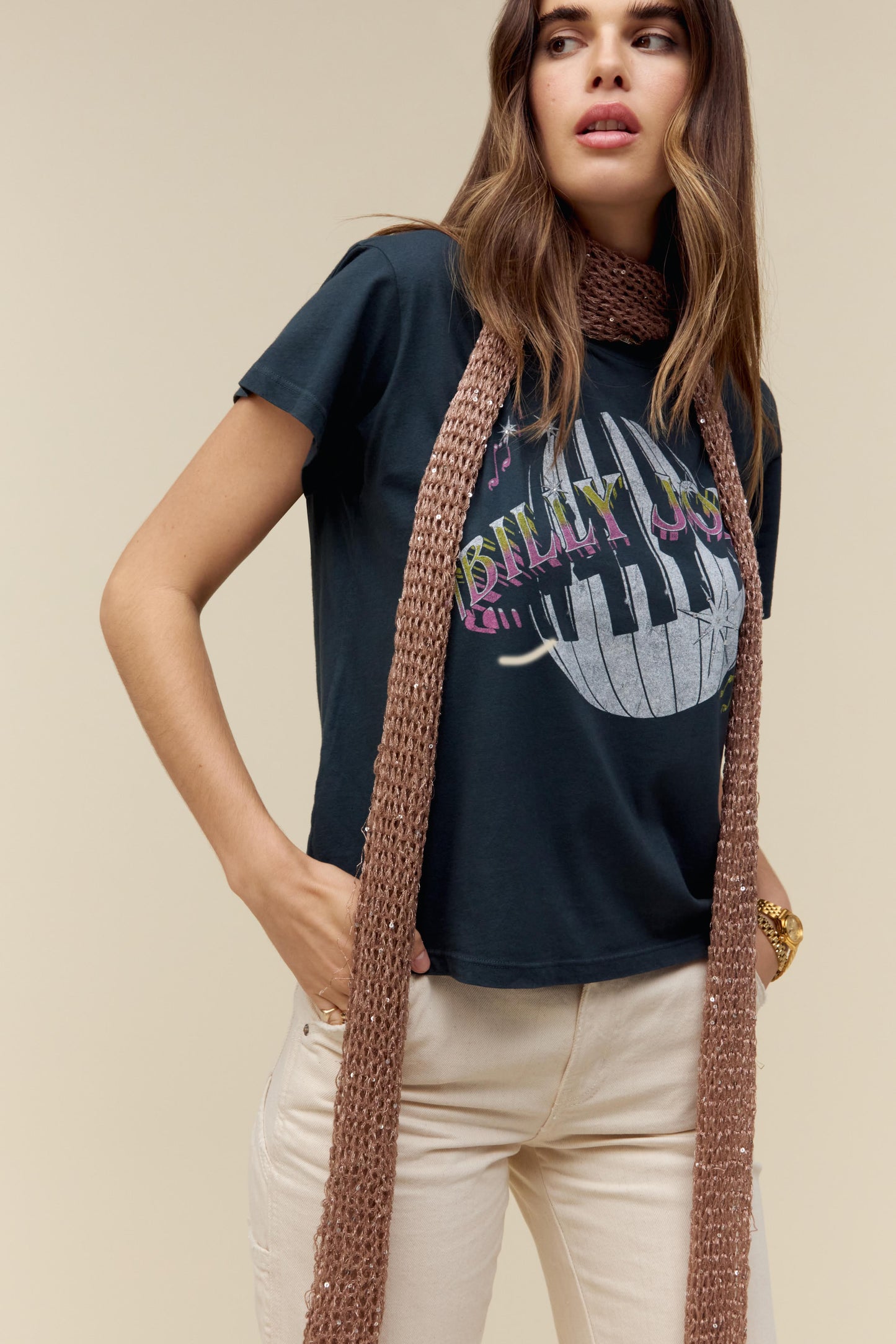 A dark-haired model featuring a black tee designed with piano keys wrapped around a disco ball and the icon’s name spelled out in bold text.