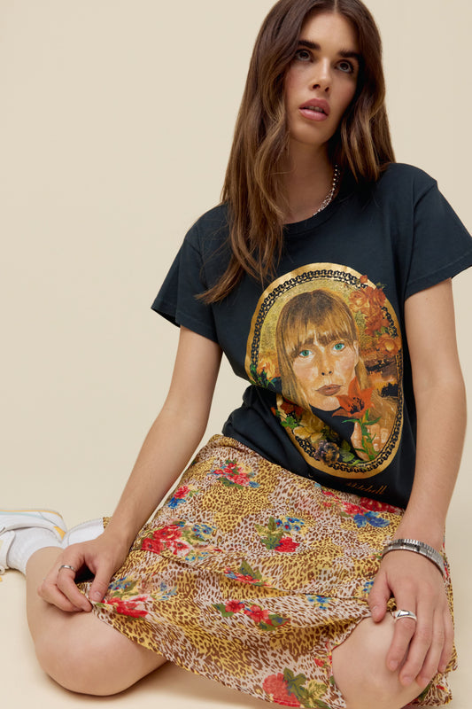 A model featuring a vintage black Joni Mitchell solo tee designed with an icon of the artist herself accented in gold foil.