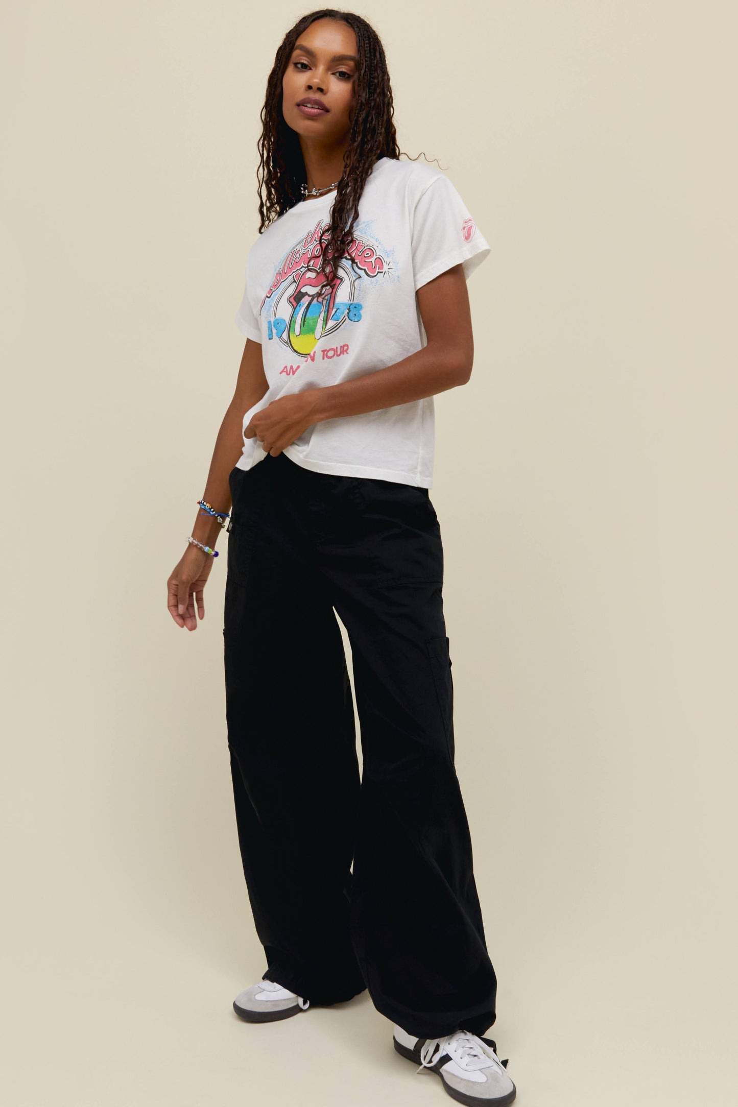 A dark-haired model featuring a white tee designed with the classic Rolling Stones logo in the center