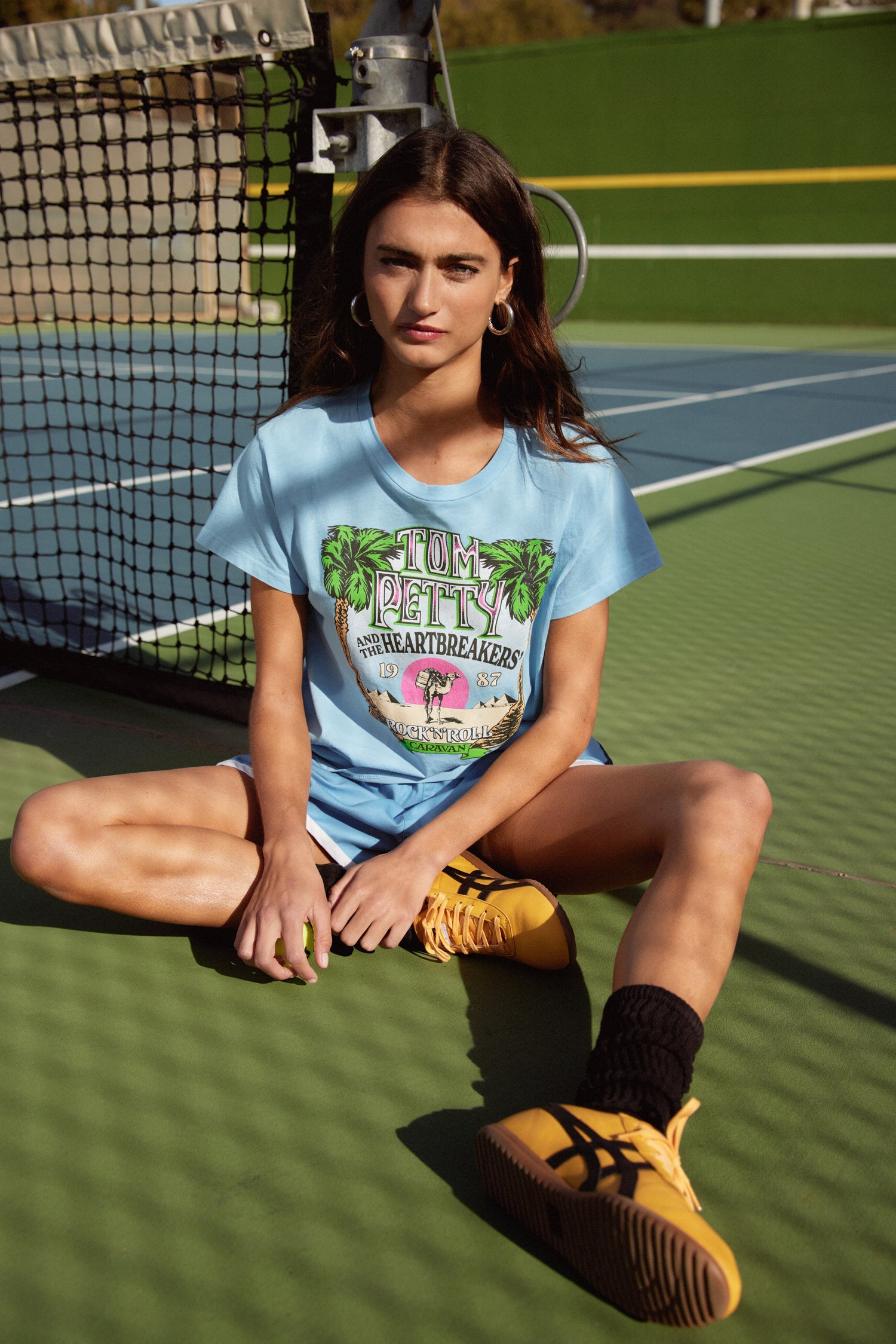 A model featuring a vintage blue solo tee  stamped with 'Tom Petty' and designed with pine trees on each side