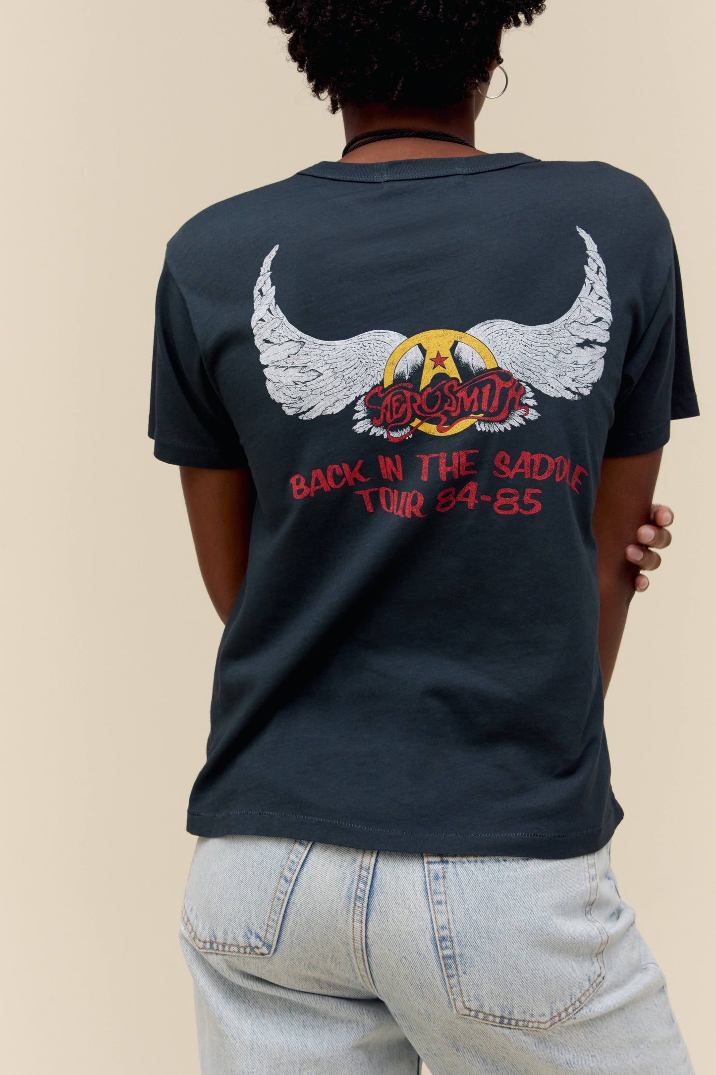A model featuring a black tee stamped with Aerosmith and a photo of the band in the middle.