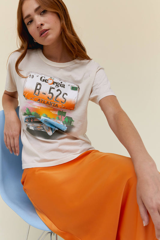 A model featuring a dirty white tee with a graphic of B-52s Love Shack Car on the center