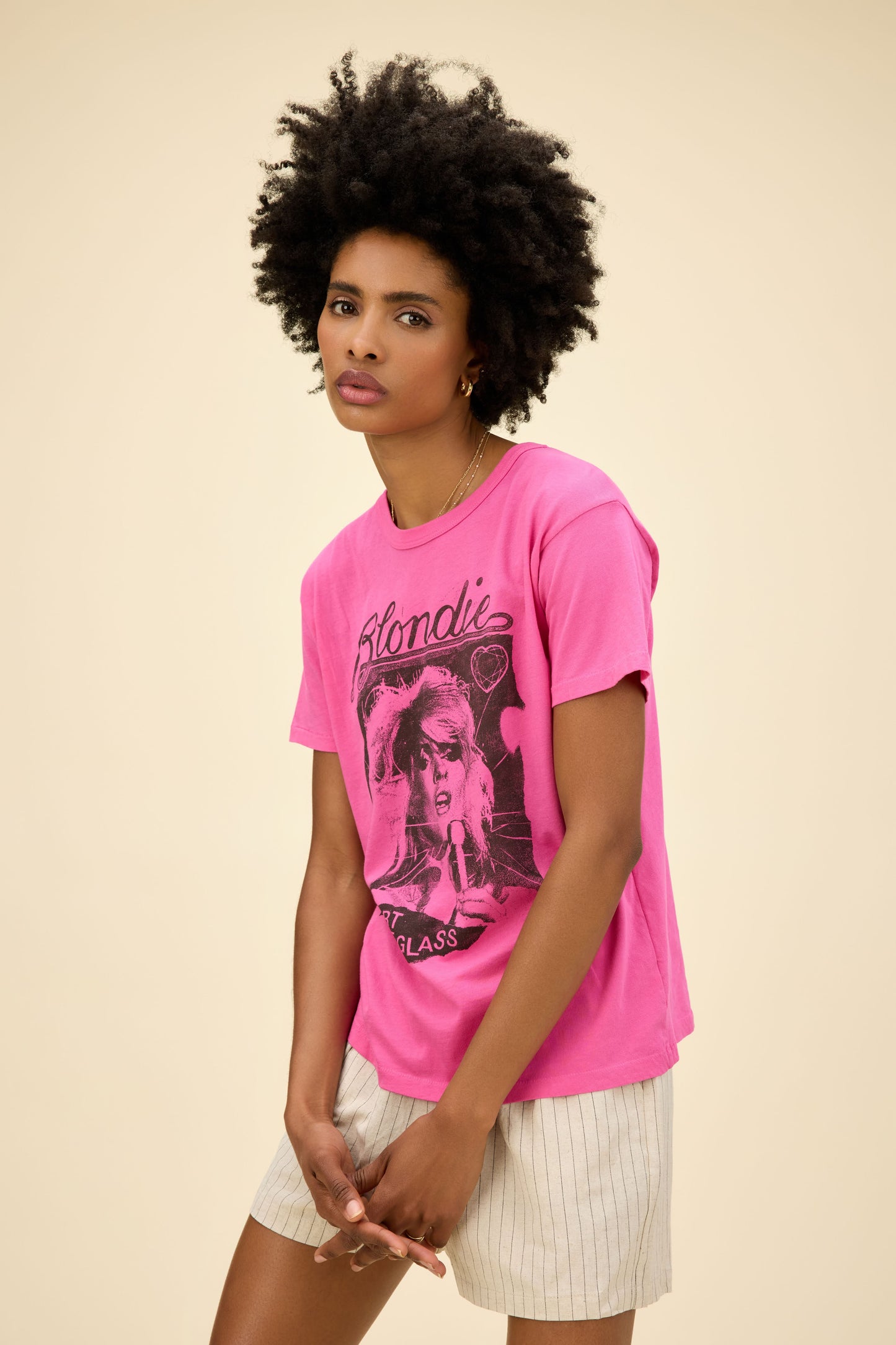 Curly-haired model wearing a Blondie graphic ringer tee in pink with 'Heart Of Glass' artwork on the front and back.