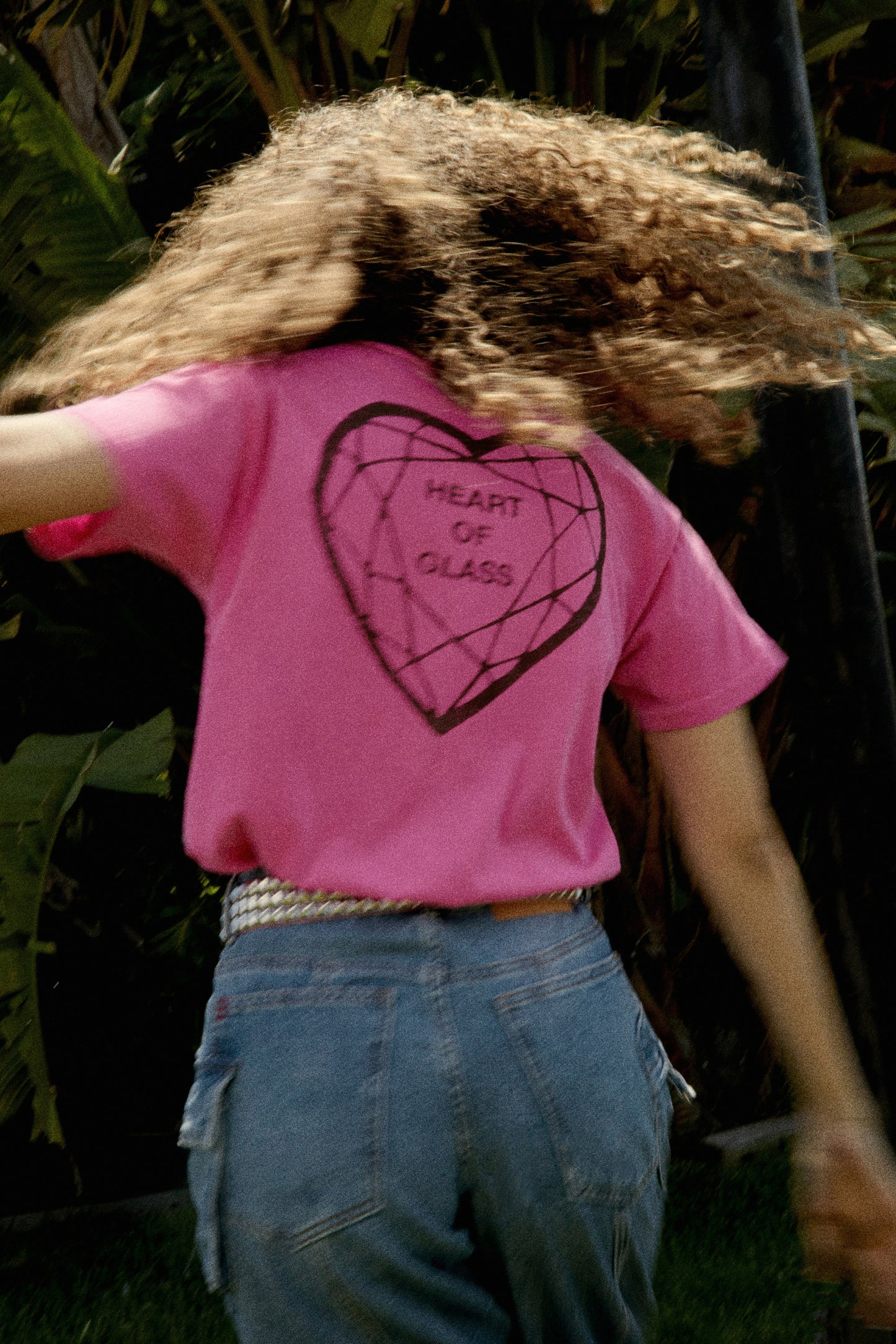 Model wearing Blondie graphic tee in pink with "Heart Of Glass" artwork on back.