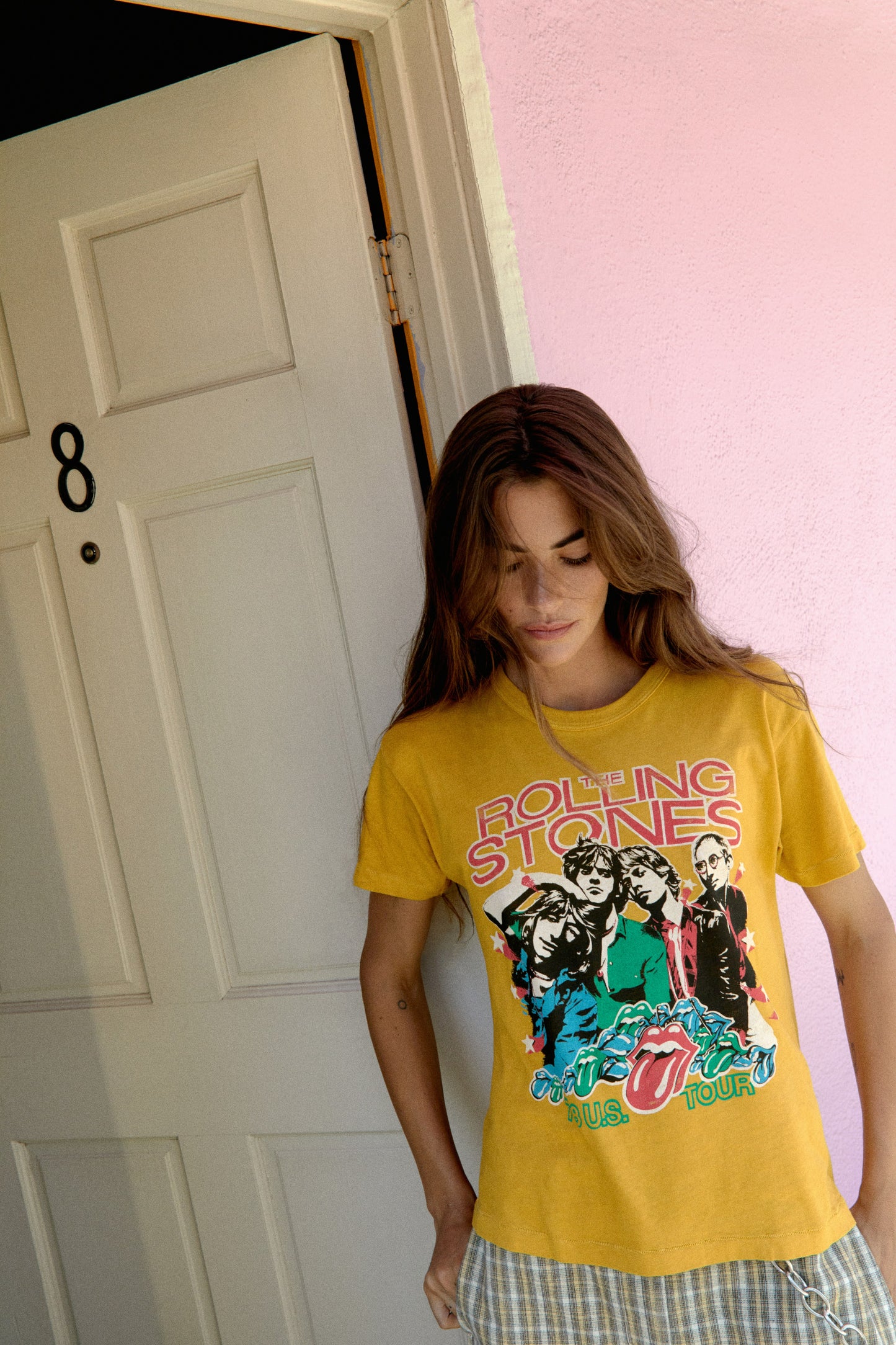 A dark-haired model featuring a golden daze tee stamped with 'The Rolling Stones' and designed with an iconic group photo of the band.