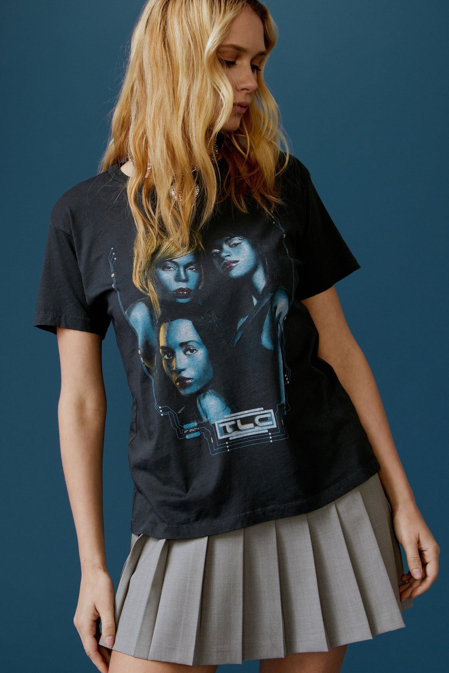 A blonde-haired model featuring a black tee designed with a portrait of each member of the group and stamped with 'TLC' at the back.