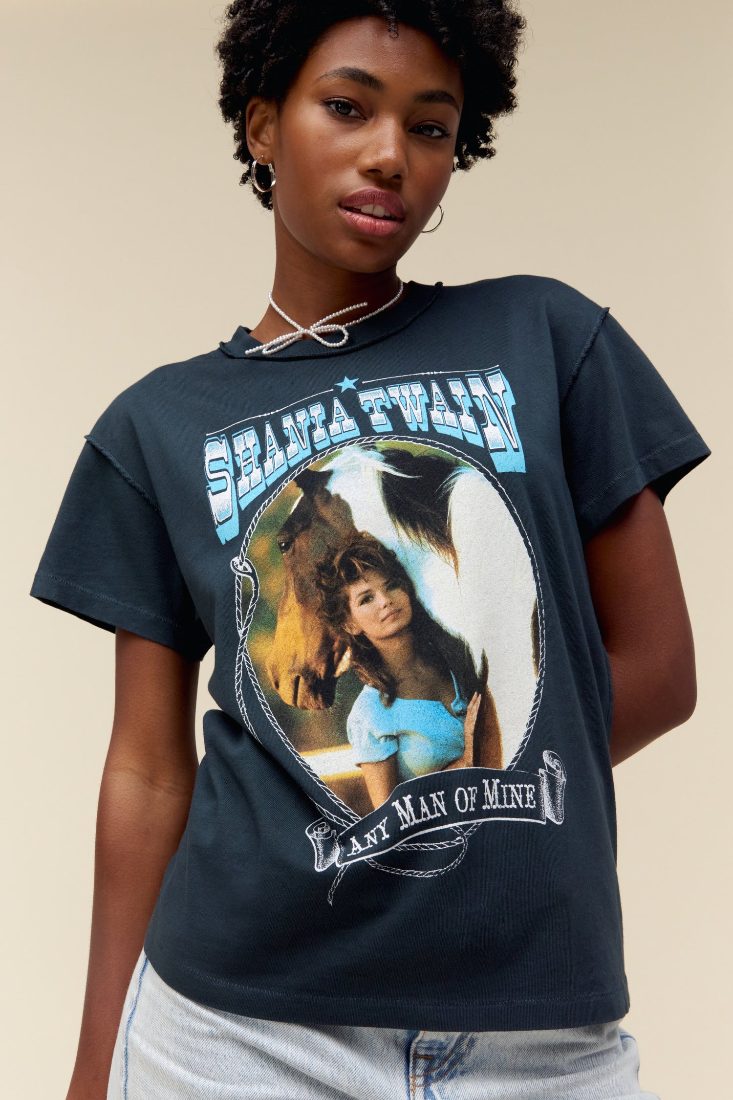 Model wearing a Shania Twain 'Any Man of Mine' graphic tee in vintage black with a reverse seam construction and portrait artwork of the iconic country singer