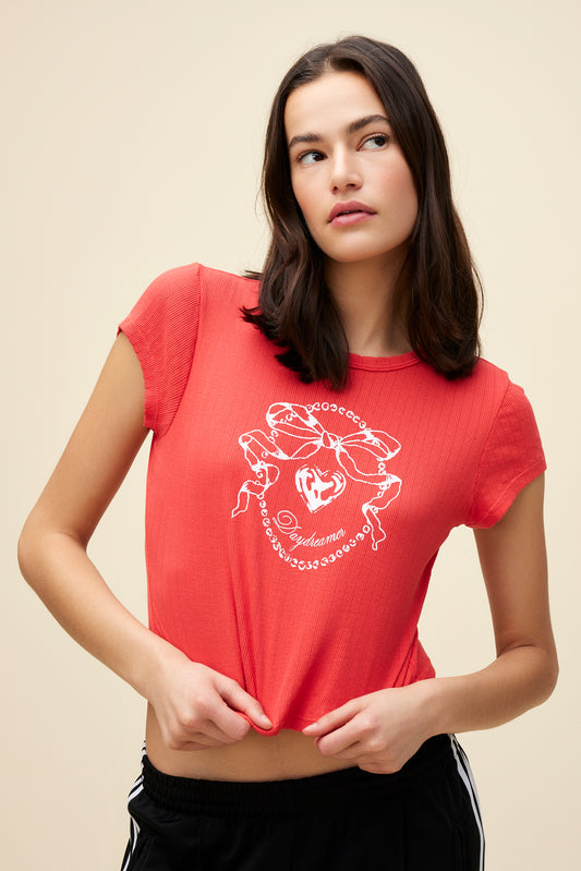 Model wearing a red pointelle baby tee with a bow graphic and 'Daydreamer' logo script on the front.