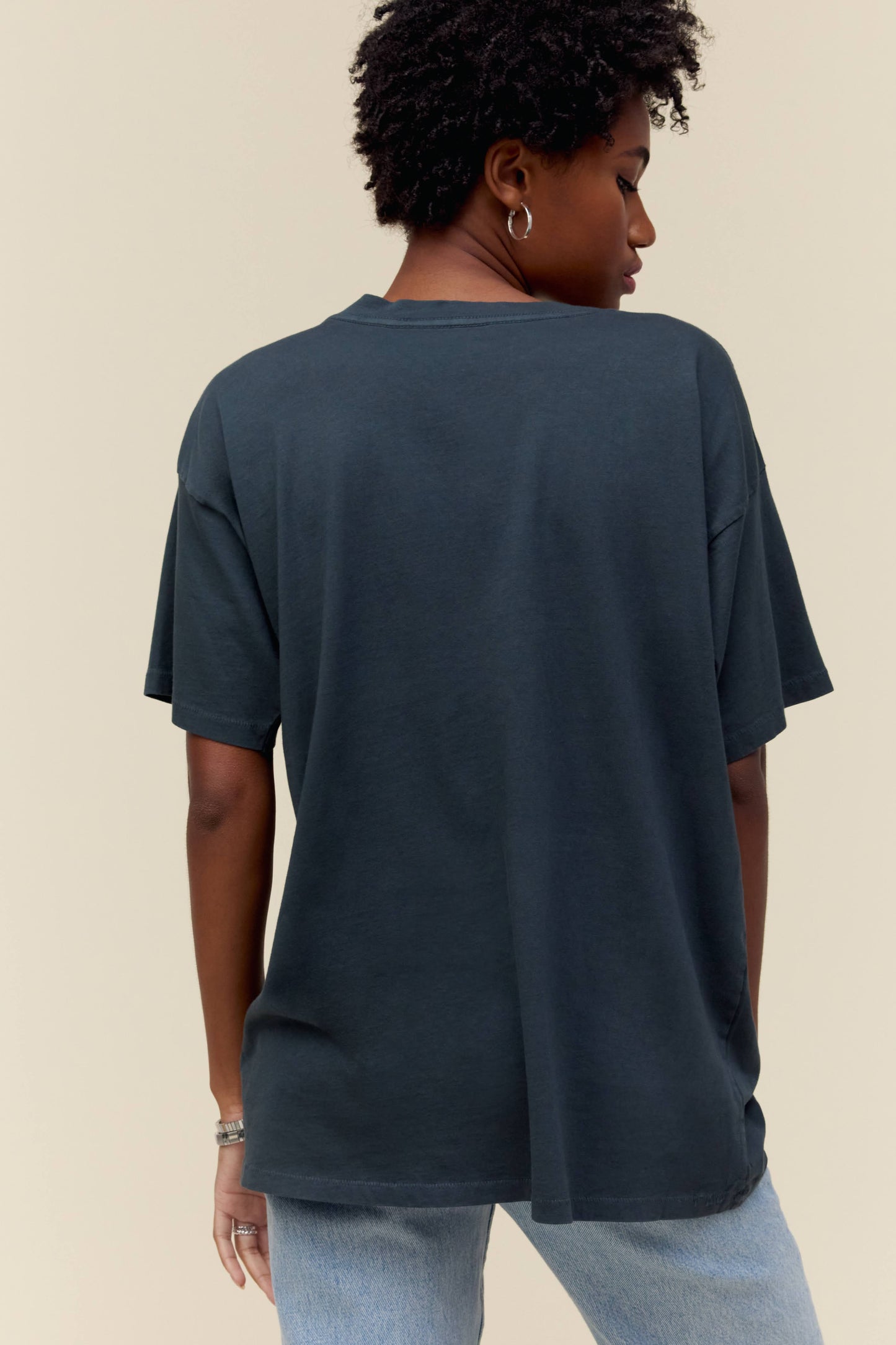 A model featuring a black tee designed with an iconic portrait of the main members and stamped with the bands name and song.