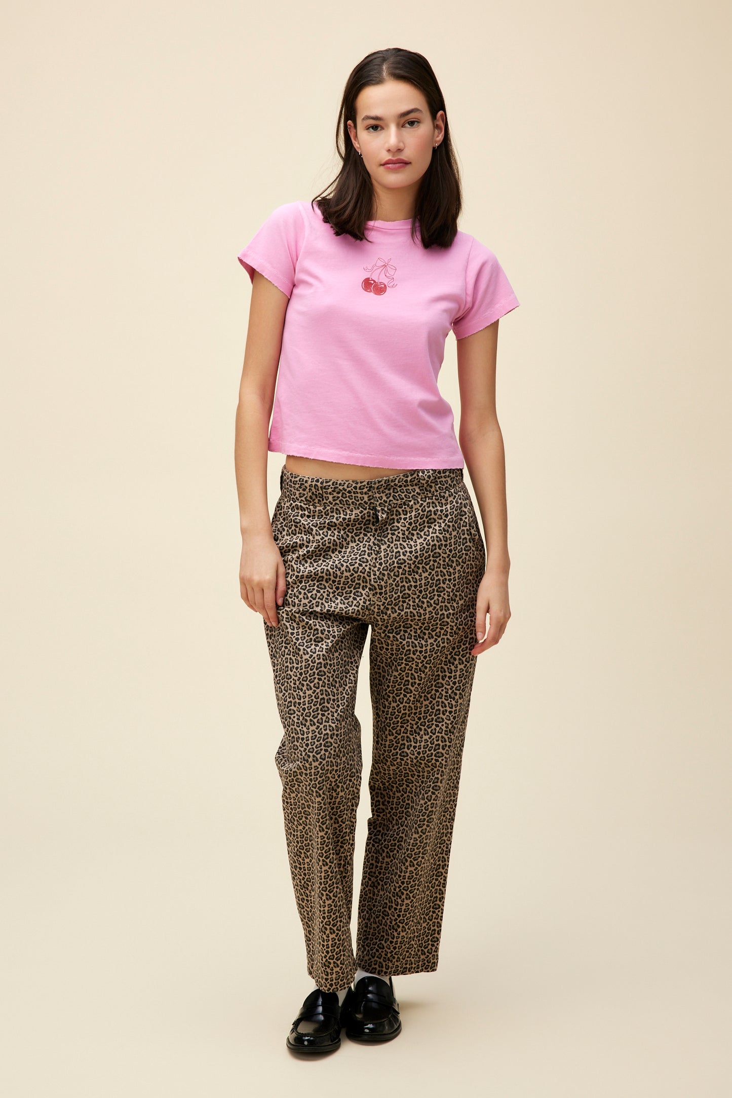 Model wearing a vintage-washed pink t-shirt with subtle grinding details and a cherry graphic on the front.