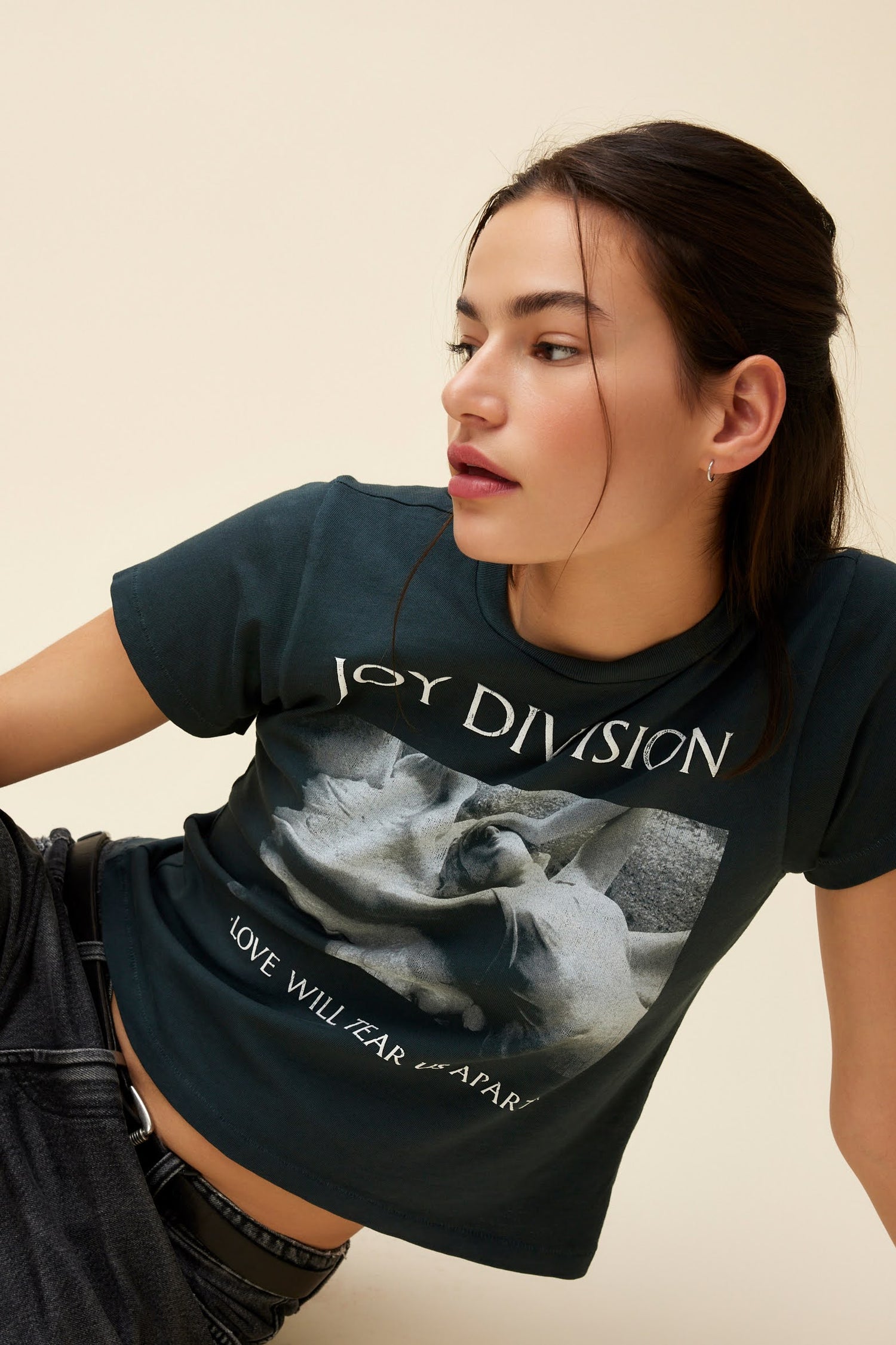 Model wearing a fitted graphic tee with Joy Division 'Love Will Tear Us Apart' artwork and a slightly cropped length.