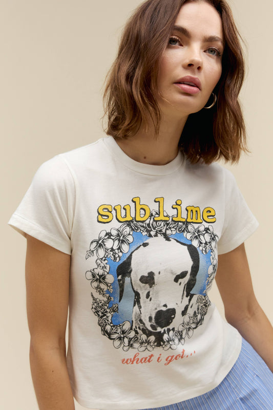 A model featuring a white tee stamped with sublime in yellow font and a graphic dog on the center.