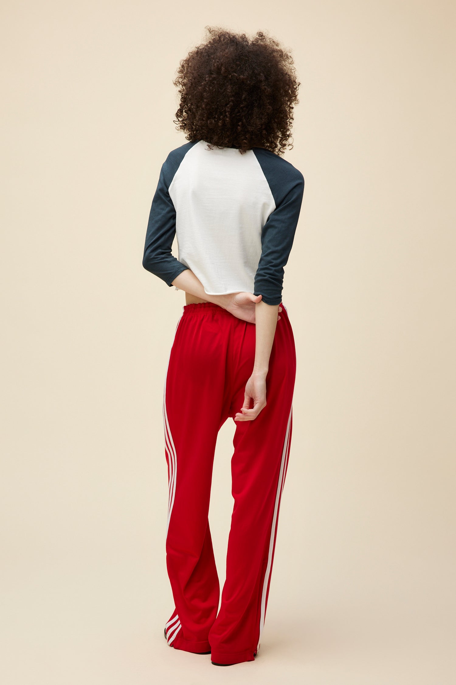 A curly-haired model wears a vintage-inspired long sleeve raglan tee with a red cherry graphic on the front.