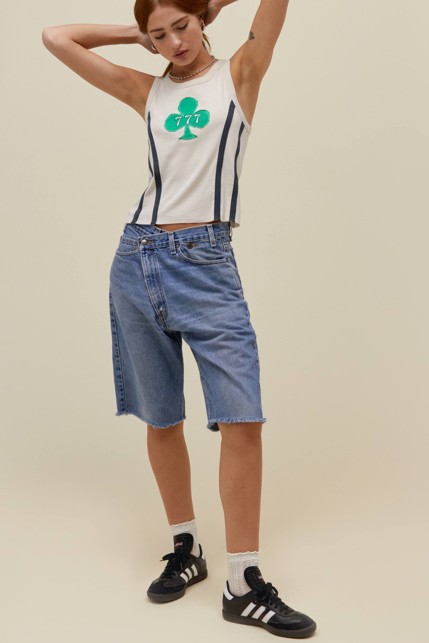 A  model wearing a tank top featuring a semi-medium clover leaf with the numbers 777 on it font 