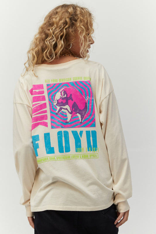 Blonde curly-haired model featuring a white-colored long sleeve designed with psychedelic-inspired block letters and a stamp of Pink Floyd’s inflatable pig, Algie, accented in pink and green puff ink