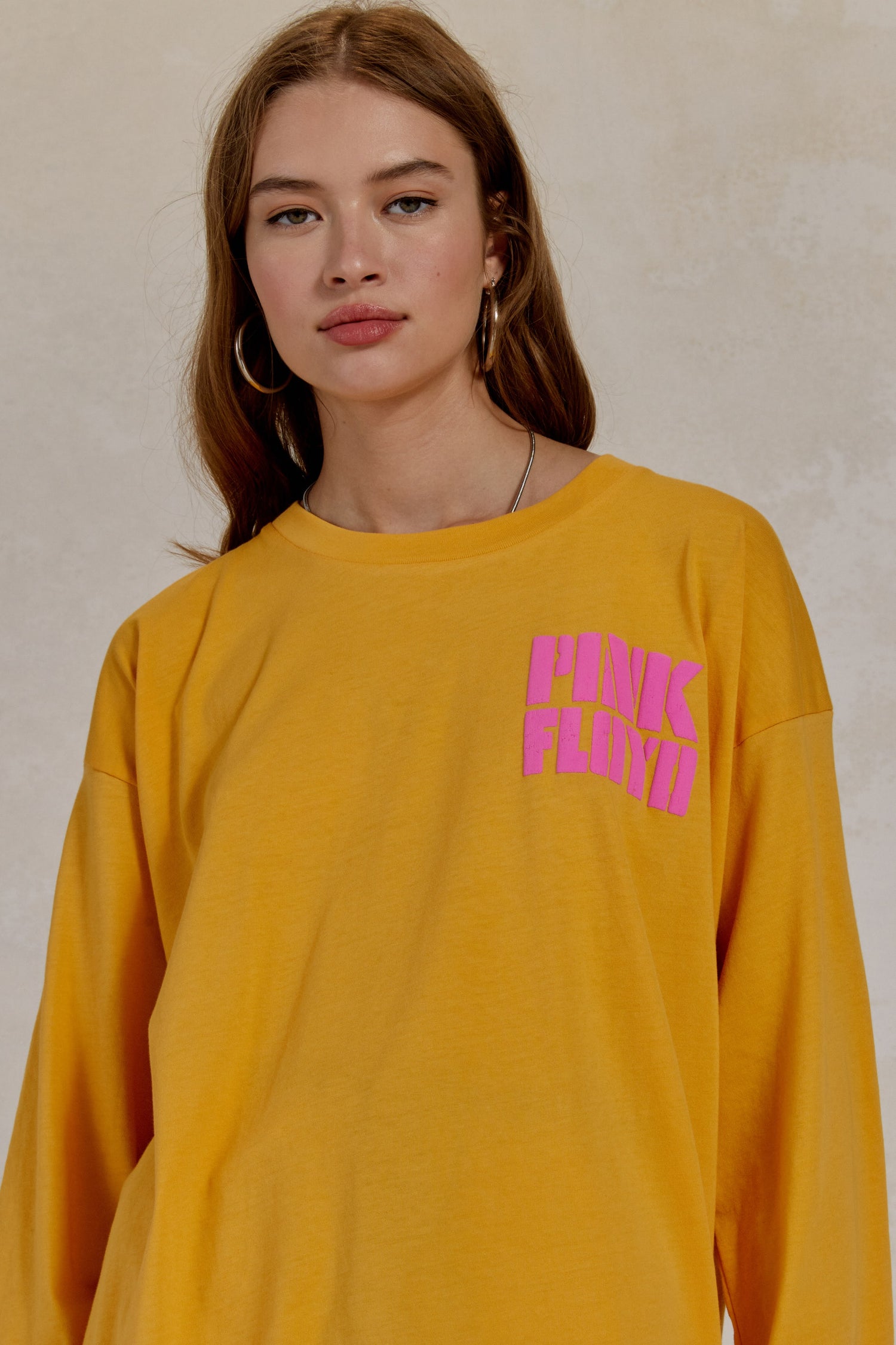 Dark wavy-haired model featuring a mango-colored long sleeve